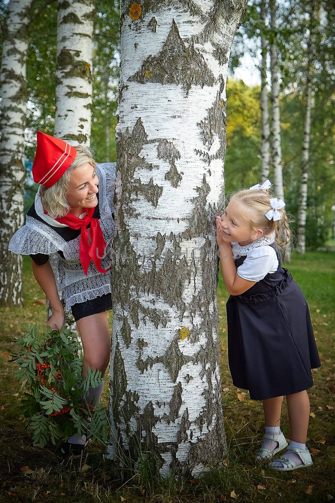 Young and adult schoolgirl on September 1, mother and daughter having fun together. Generations of schoolchildren of USSR and Russia. Female pioneer in red tie and October girl in modern uniform by keleny