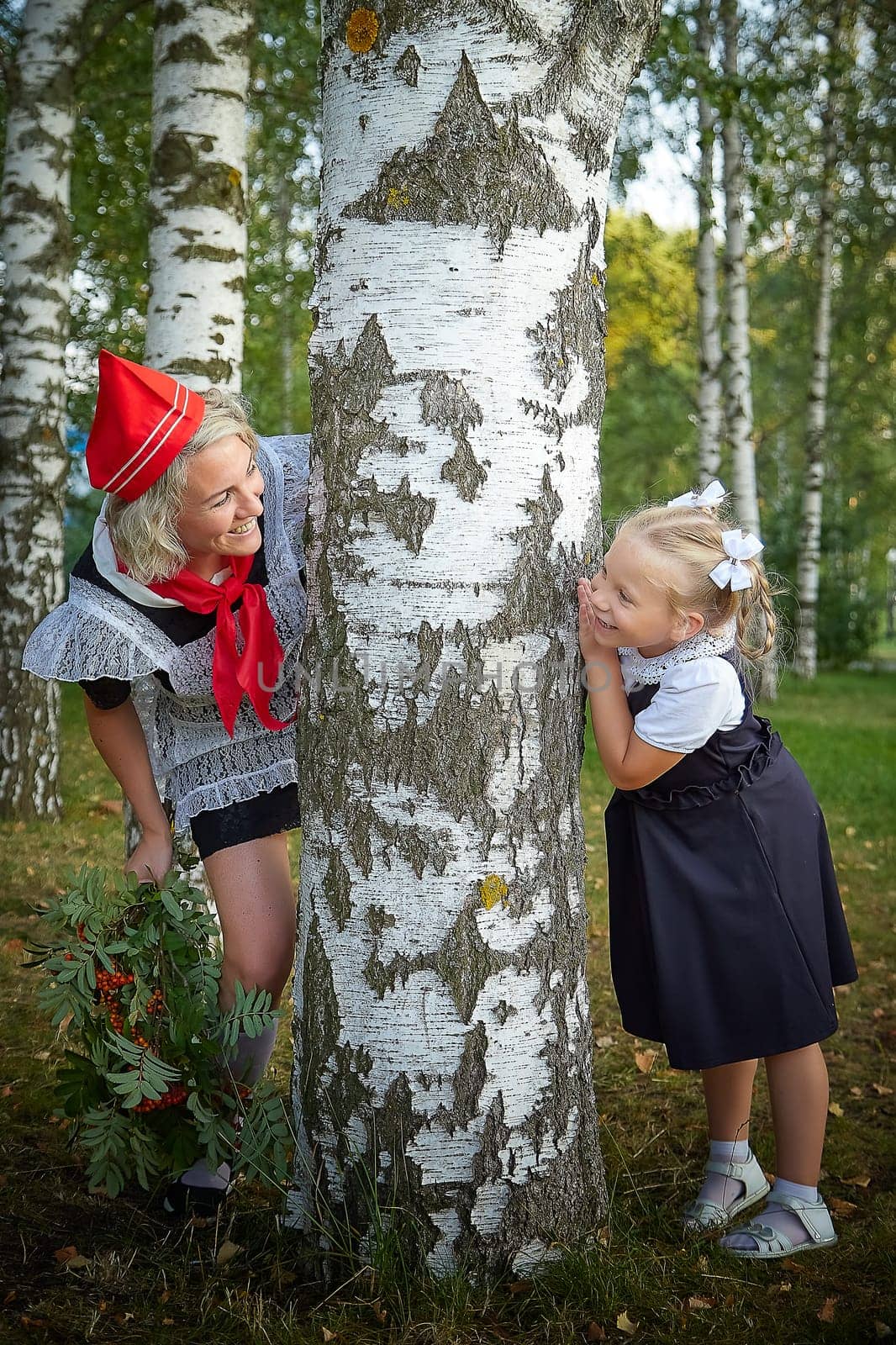 Young and adult schoolgirl on September 1, mother and daughter having fun and joy. Generations of schoolchildren of USSR and Russia. Female pioneer in red tie and October girl in modern uniform