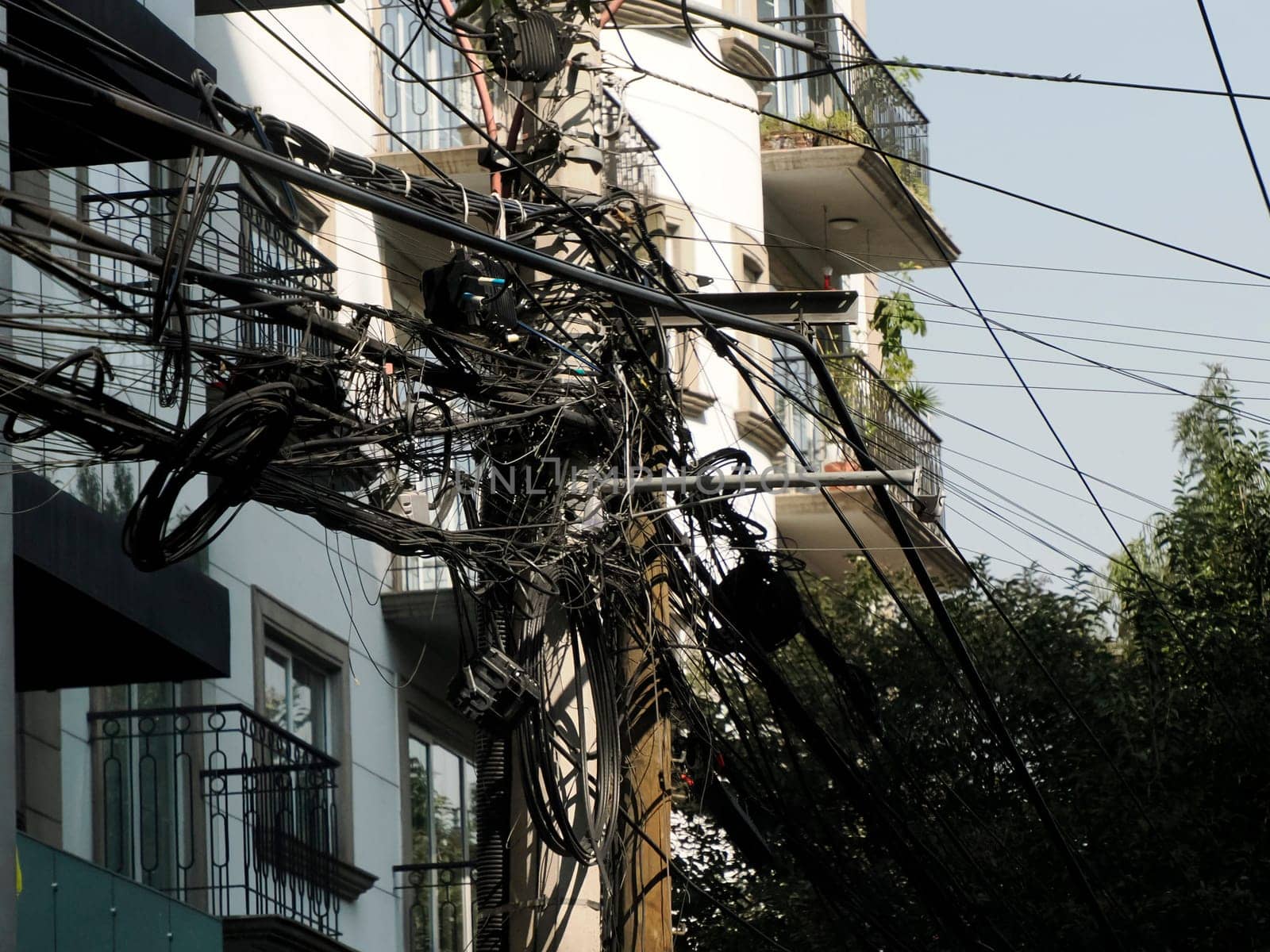 Mexico City Messed up power lines and connection cables. Many tangled wires on electric poles in the city by AndreaIzzotti