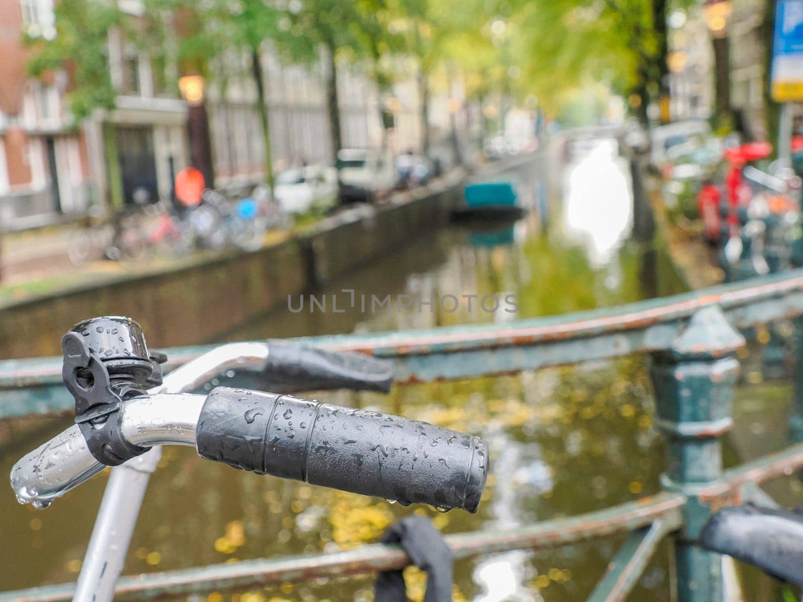 A bicycle handlebar on canals of Amsterdam view on rainy day