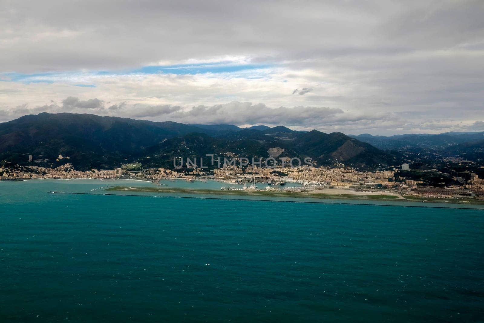 Airport of Genoa aerial view before landing to airport by airplane during a sea storm tempest hurricane by AndreaIzzotti