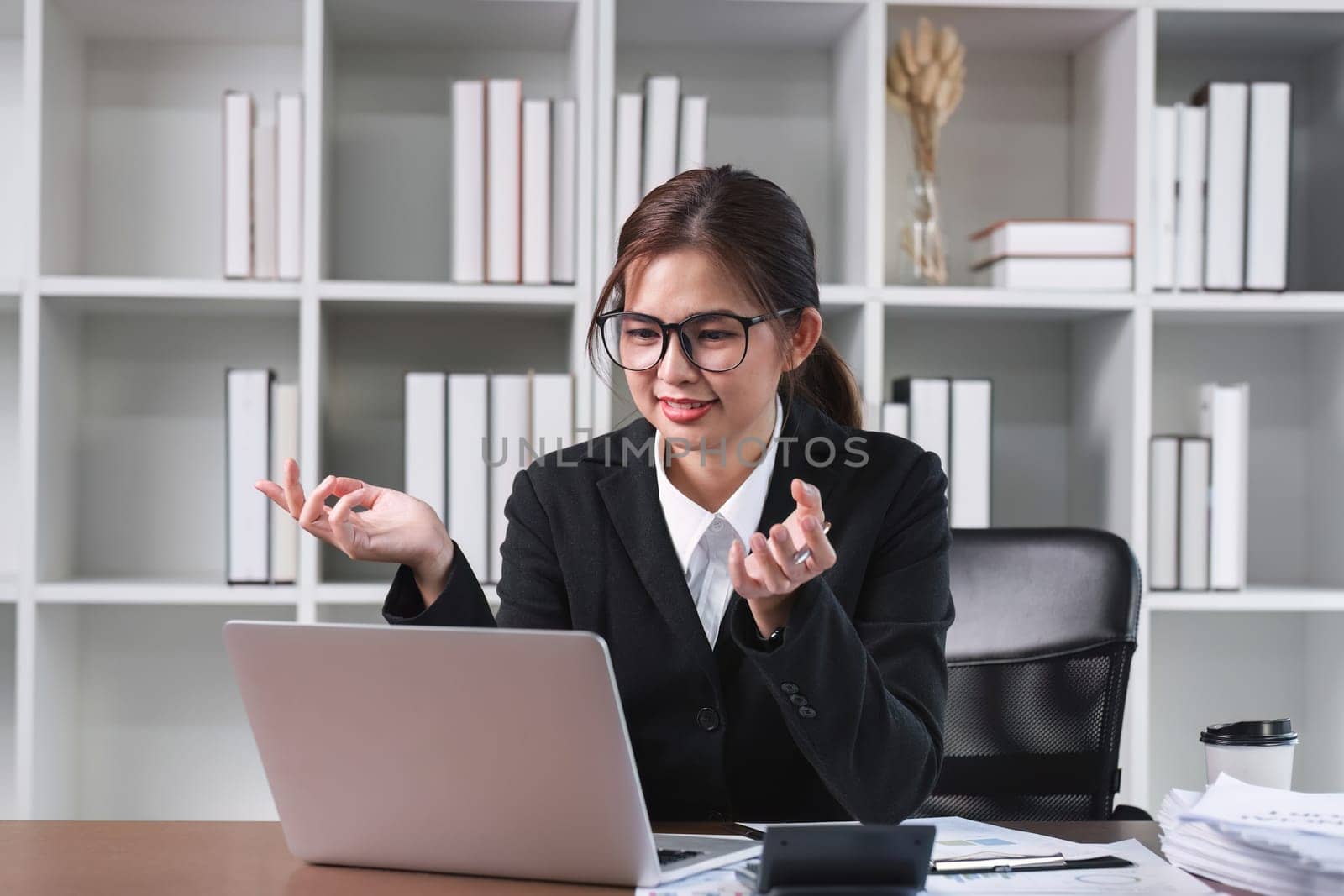 Young Asian woman using laptop to do financial transaction and plan finances and investments through online banking by wichayada