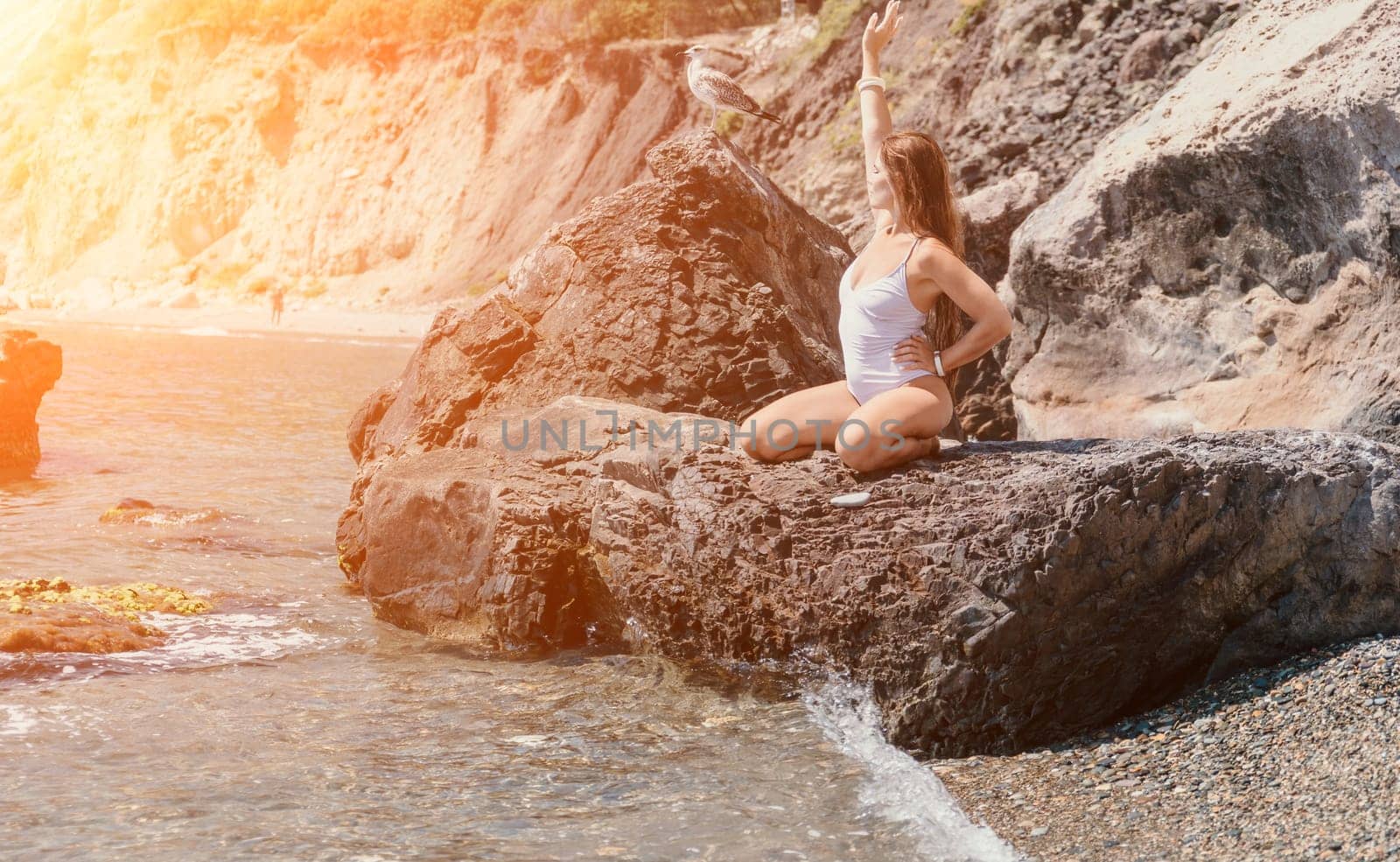 Woman travel sea. Young Happy woman in a long red dress posing on a beach near the sea on background of volcanic rocks, like in Iceland, sharing travel adventure journey