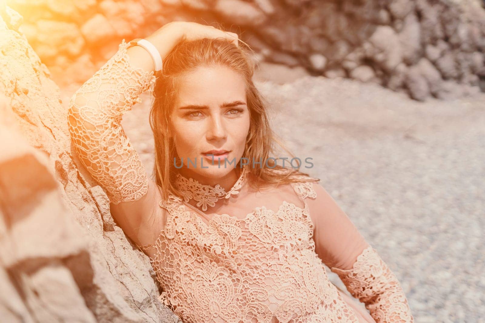 Woman summer travel sea. Happy tourist in beige dress enjoy taking picture outdoors for memories. Woman traveler posing on the beach surrounded by volcanic mountains, sharing travel adventure journey by panophotograph