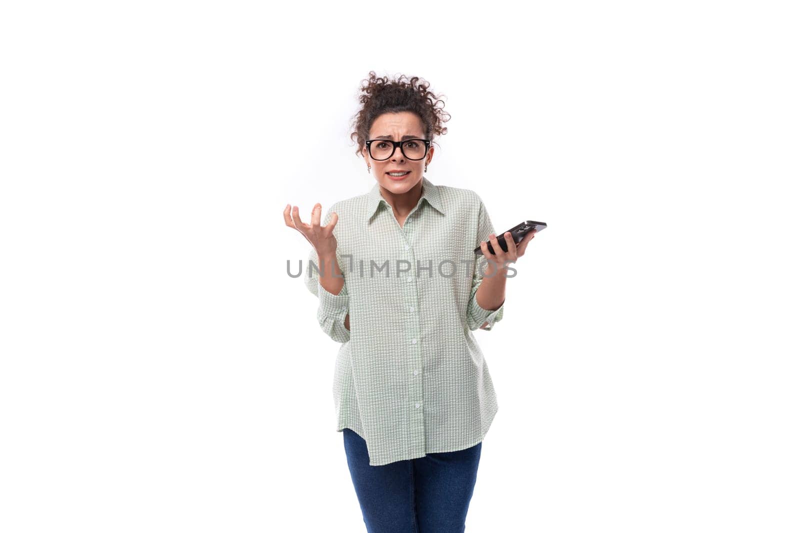 young pretty brunette woman in glasses is upset and holds a mobile phone in her hand.