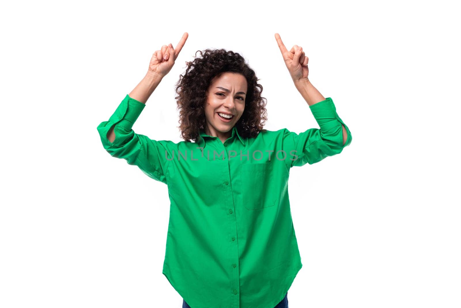 young office woman with curly hair dressed in a green shirt points her fingers up by TRMK