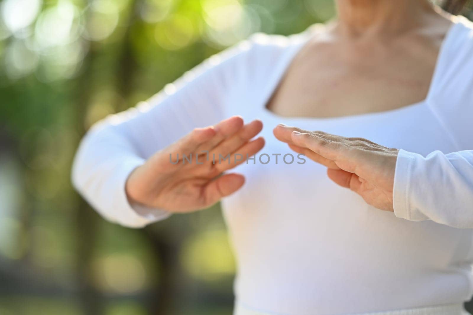 Cropped shot senior woman practicing Chi Kung or Tai Chi in nature. Healthy lifestyle concept