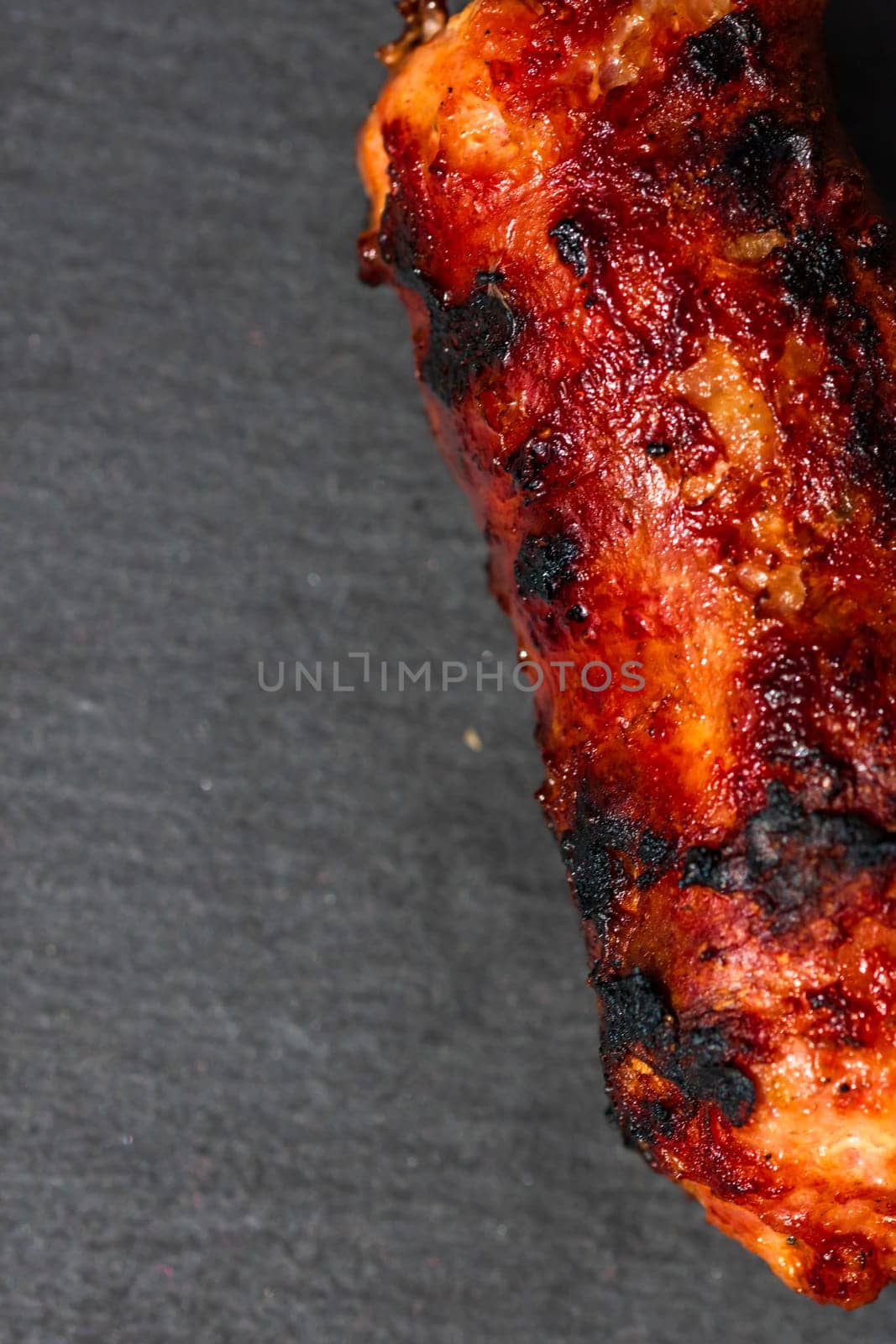 Close up of grilled sausage on small black cutting board isolated. Barbecue, grill and food concept.