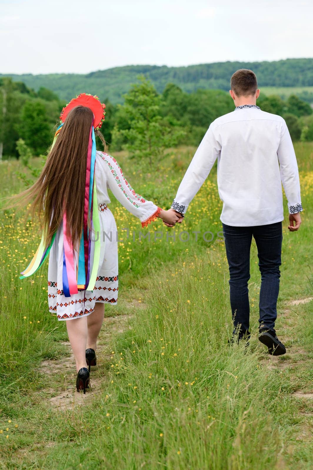 A boy and a girl ride hand in hand through the field, they are dressed in Ukrainian national clothes. by Niko_Cingaryuk
