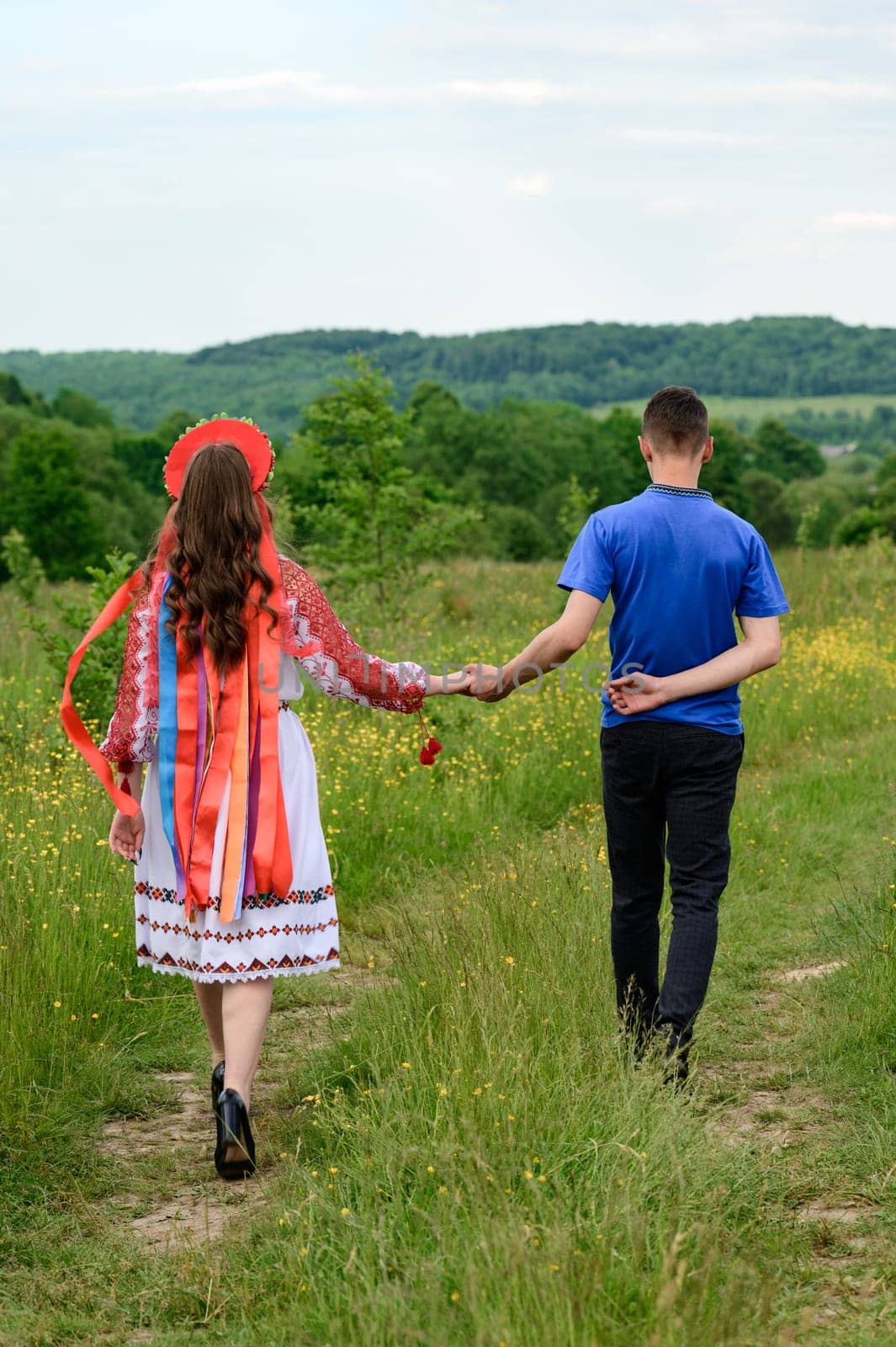A boy and a girl ride hand in hand through the field, they are dressed in Ukrainian national clothes. by Niko_Cingaryuk