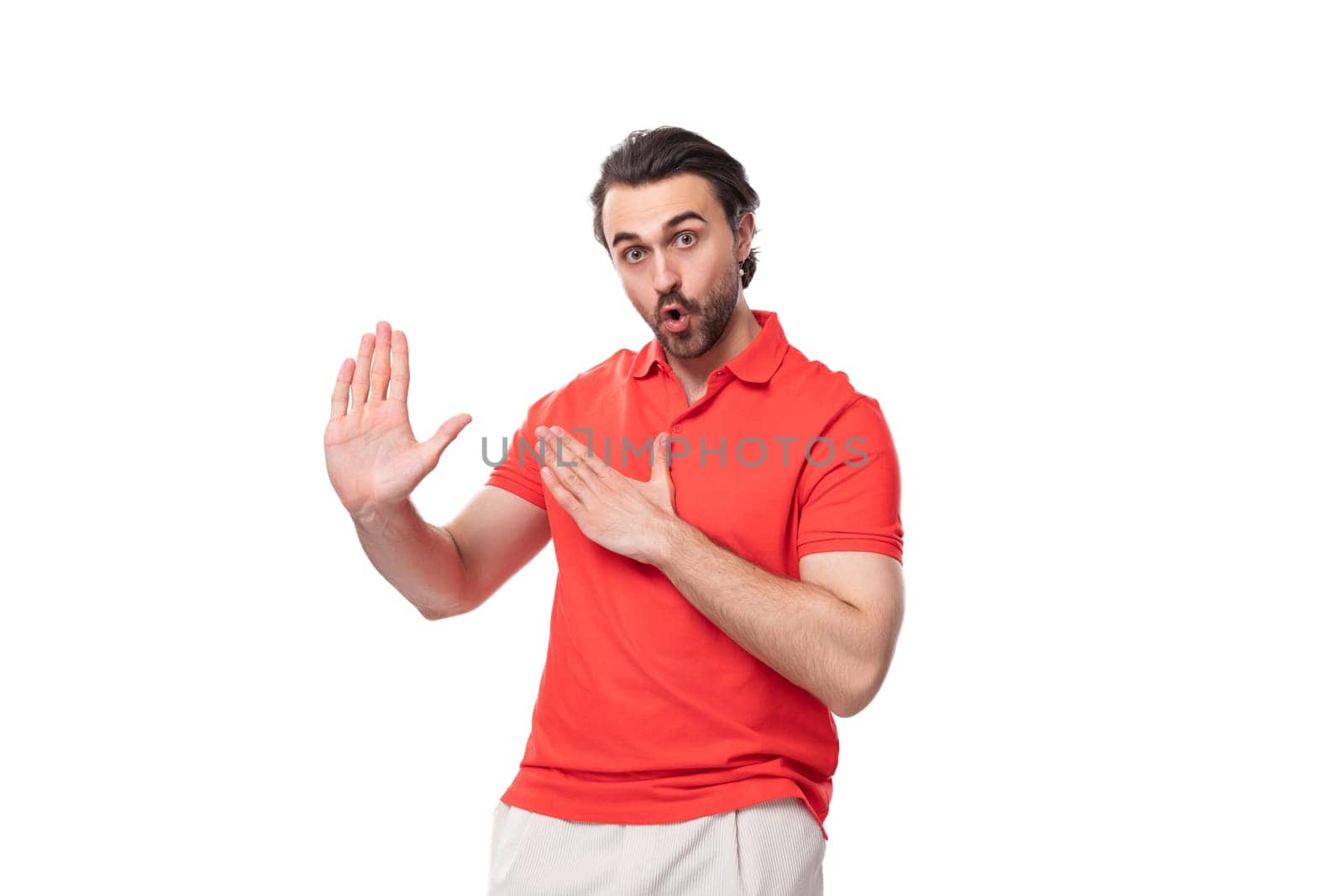 young brutal man with black hair and a beard dressed in a red t-shirt with a mockup for printing on a white background with copy space.
