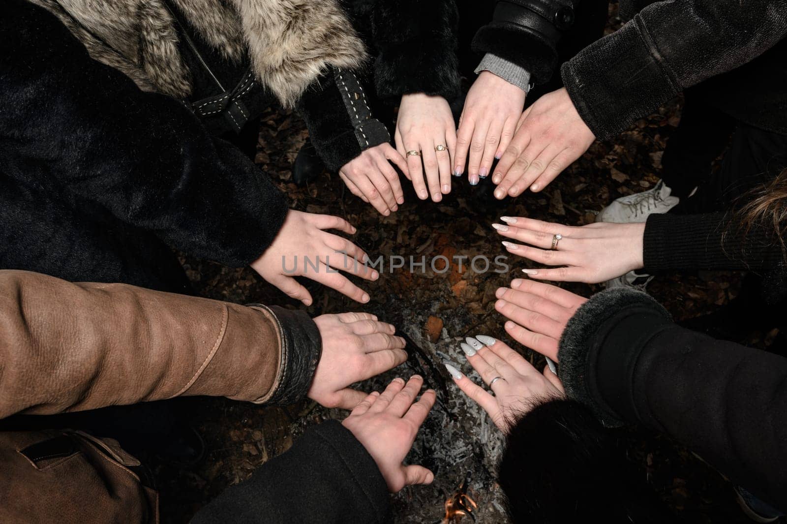 children's hands are folded with palms up in a circle, hands are held over the fire.