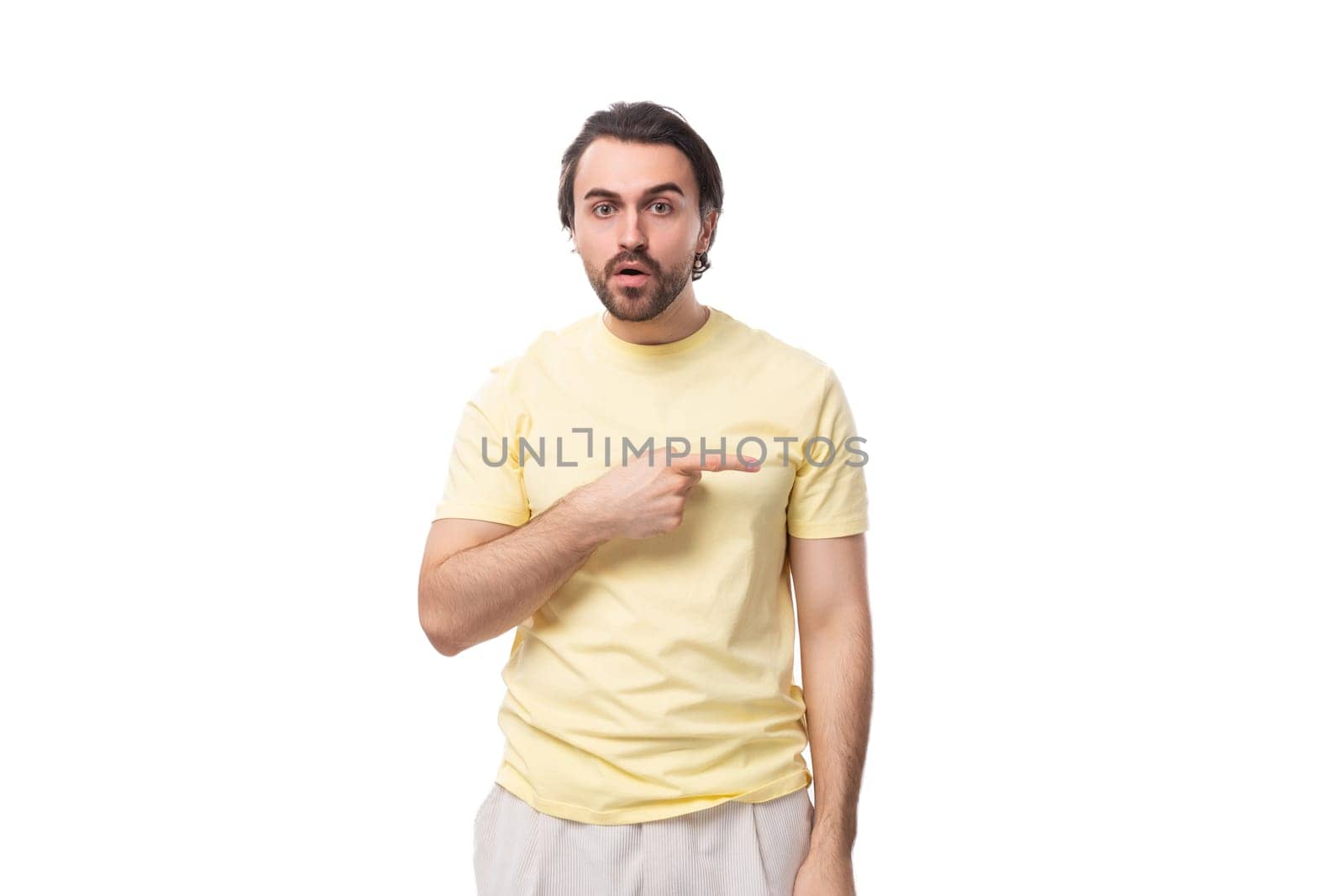 caucasian surprised brutal charming guy with a beard dressed in a summer t-shirt on a white background with copy space.
