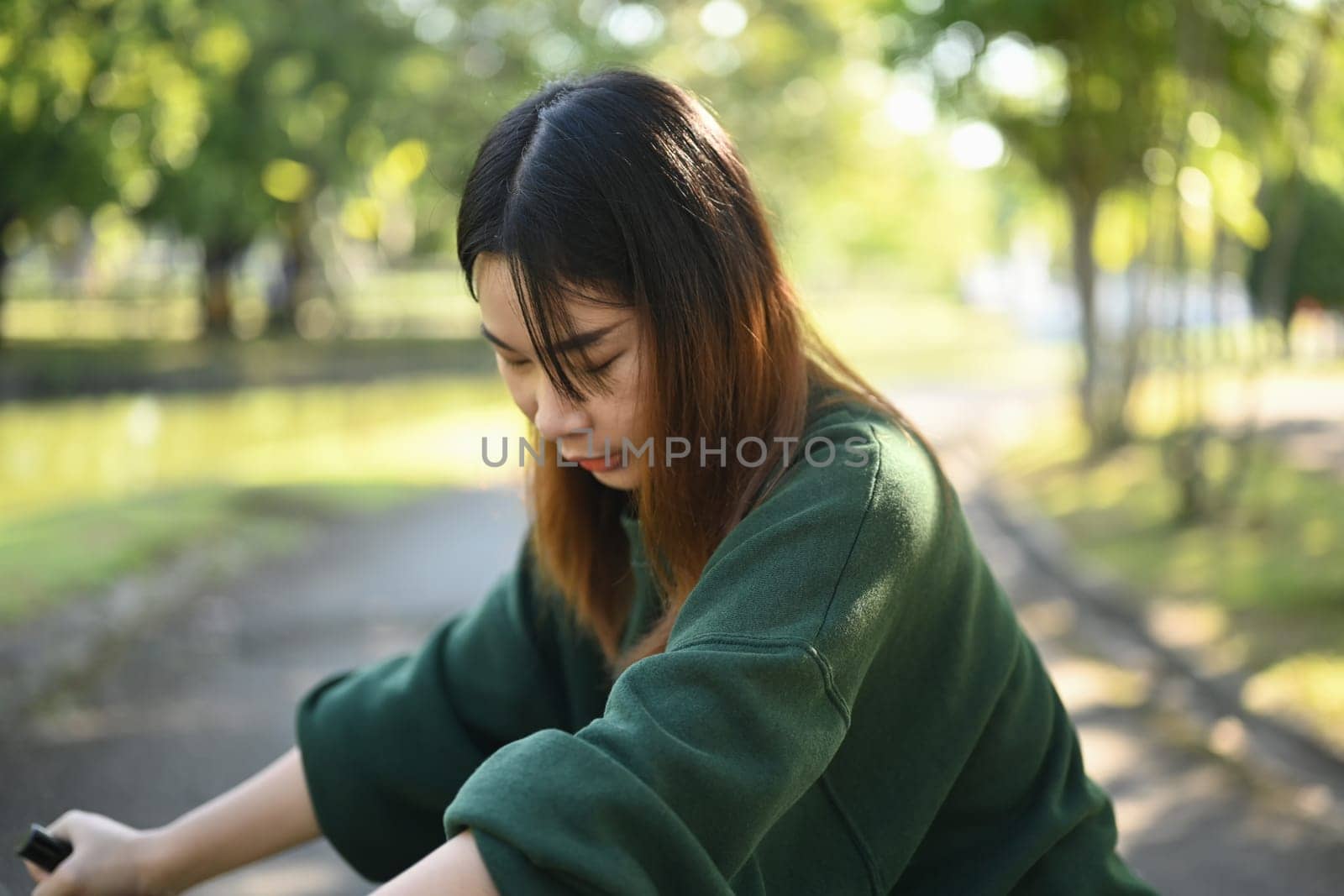 Portrait of young Asian woman riding a bicycle in the park on beautiful spring day
