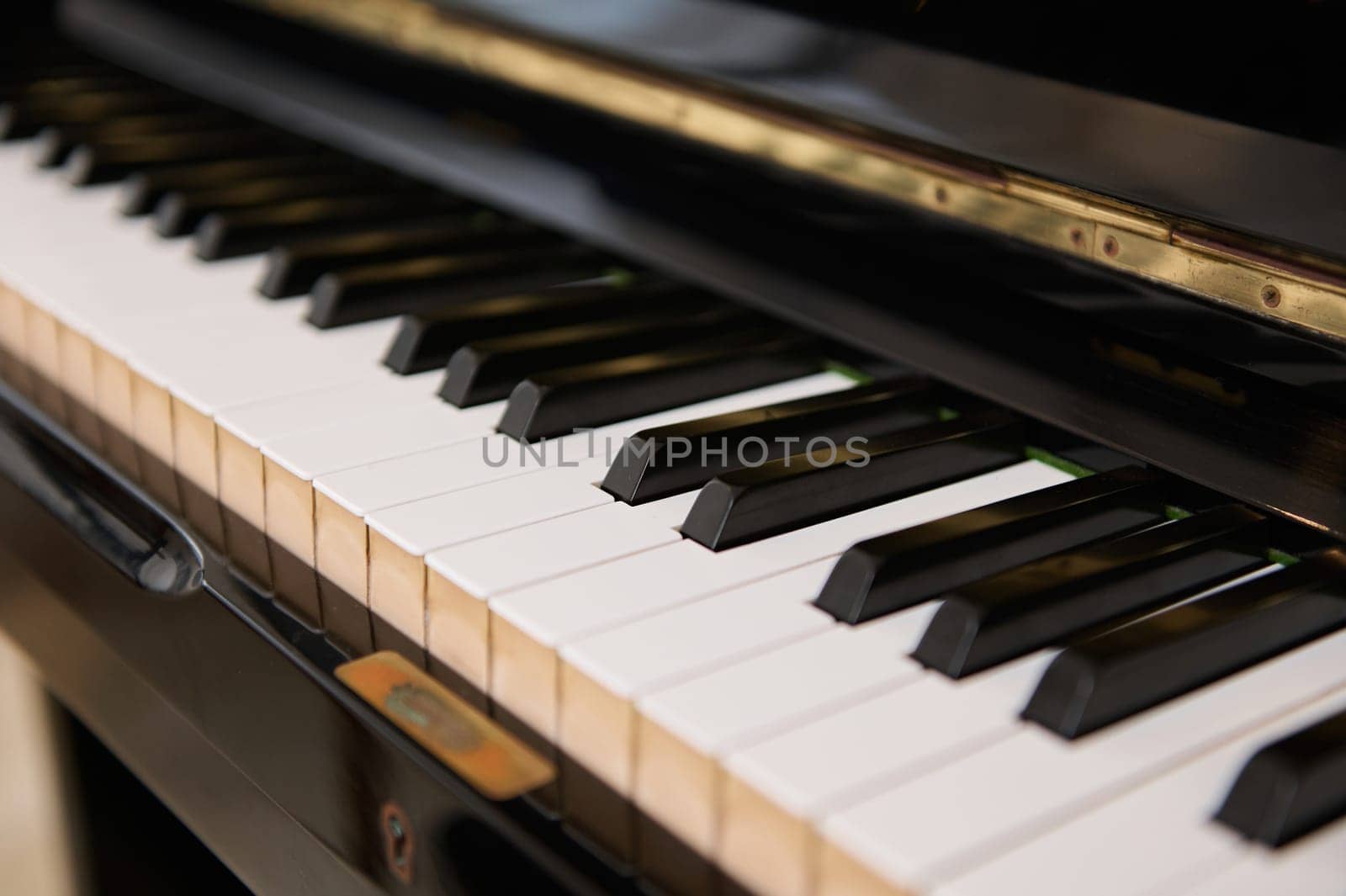 Close up shot of black wooden vintage grand piano keyboard, with black and white keys. Still life. Classic musical chord instrument