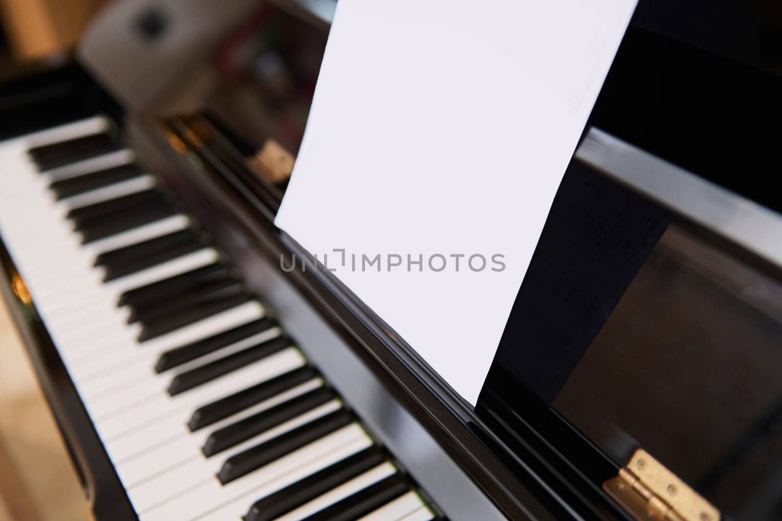 Close-up shot of classical piano and white paper sheet with music notes for performing musical composition. by artgf