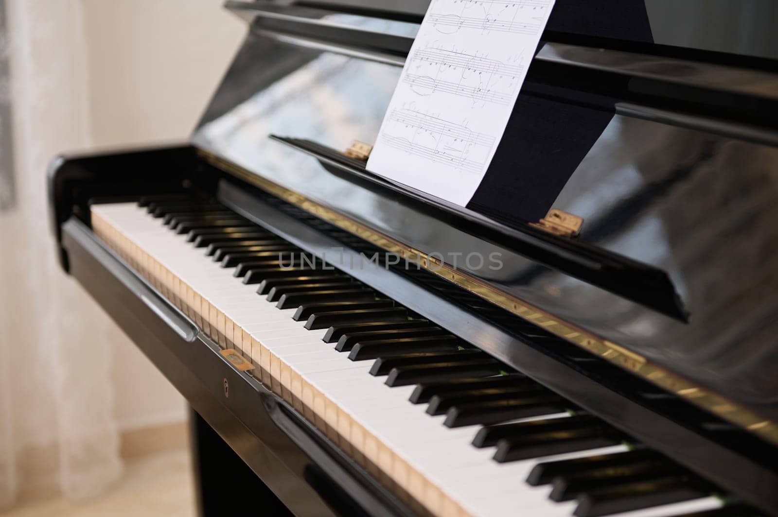 Close-up shot of old piano with open keyboard and paper sheet with notes by artgf
