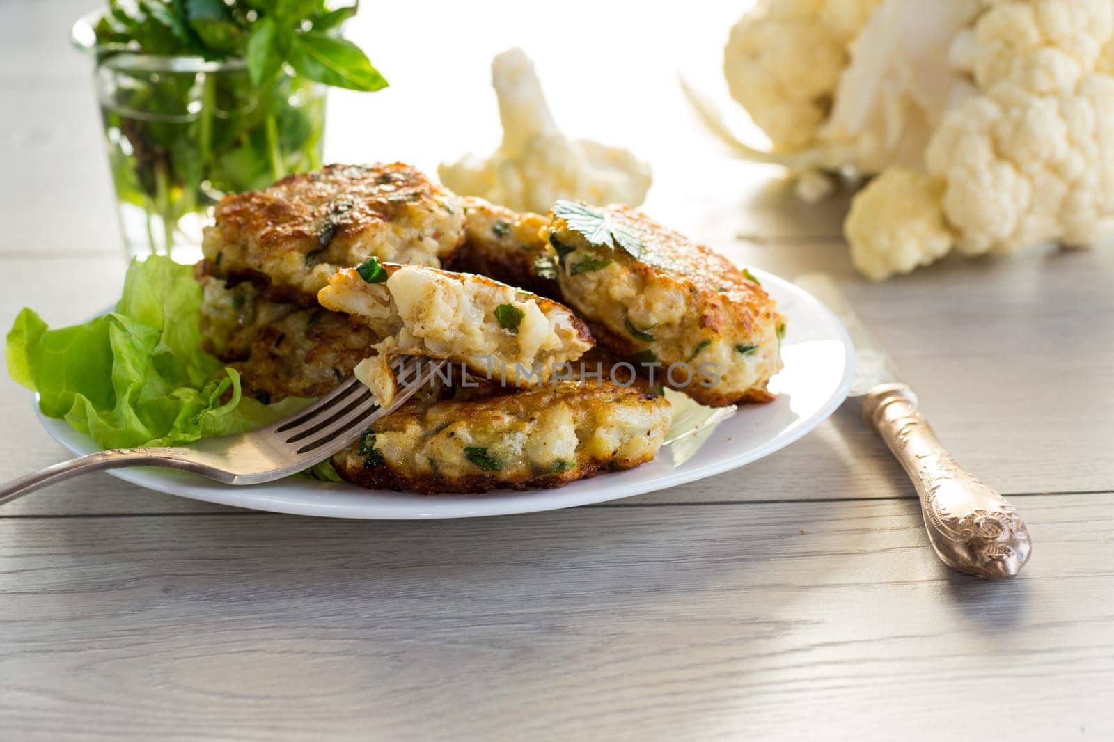 cooked vegetarian fried cauliflower cutlets, in a plate on a wooden table.