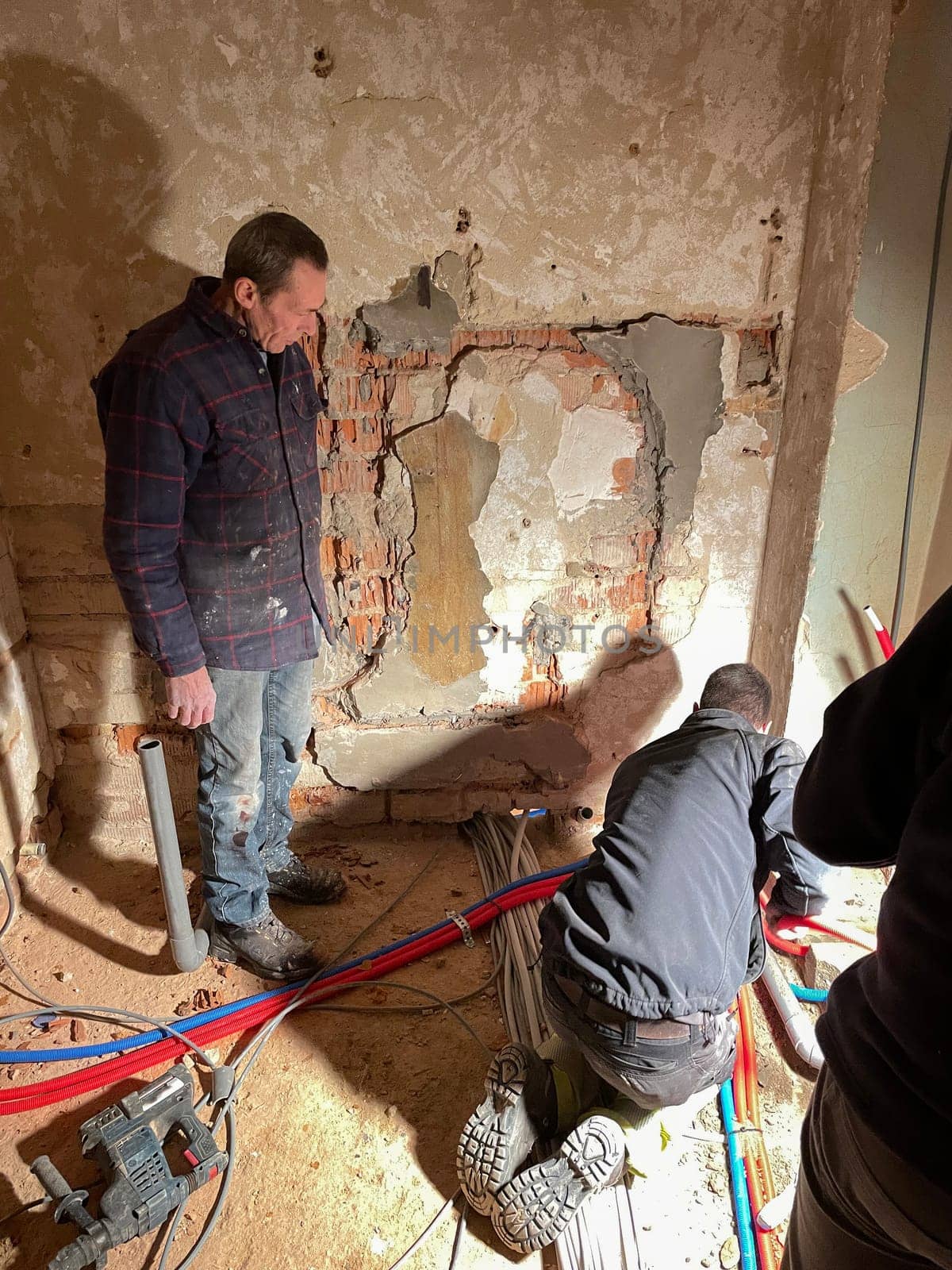 team of professional electricians is working at the construction site,operation specialists are installing wiring in the house inside the walls, High quality photo