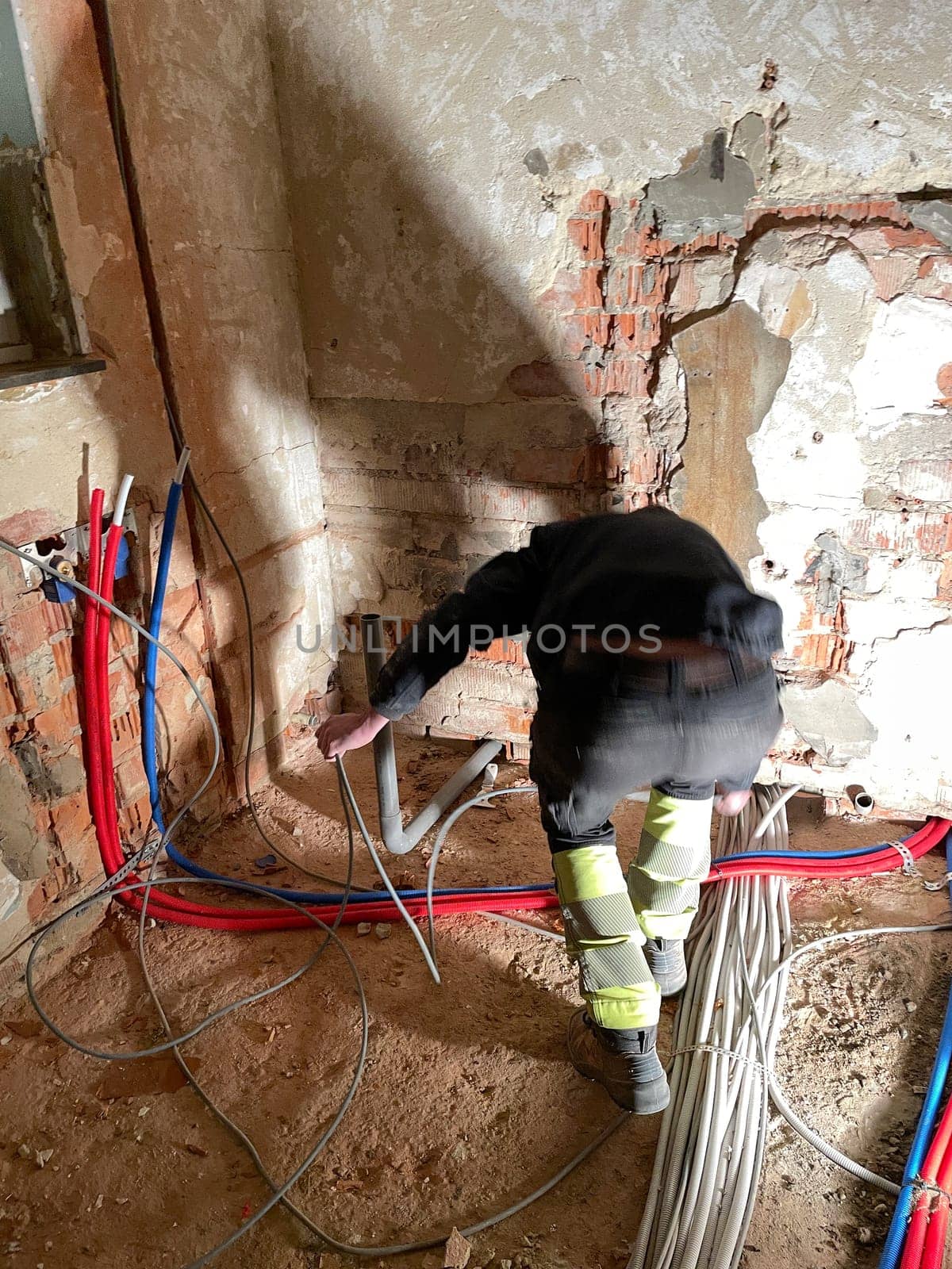 Electrician working working on building site, technicians install wiring by KaterinaDalemans