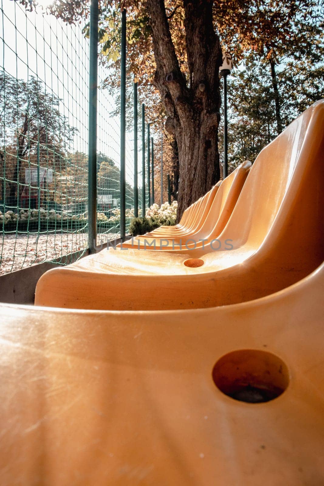 Close up yellow seats of tribune on sport stadium concept photo. Chairs for audience in park. Cultural environment concept. Empty seats, modern stadium.