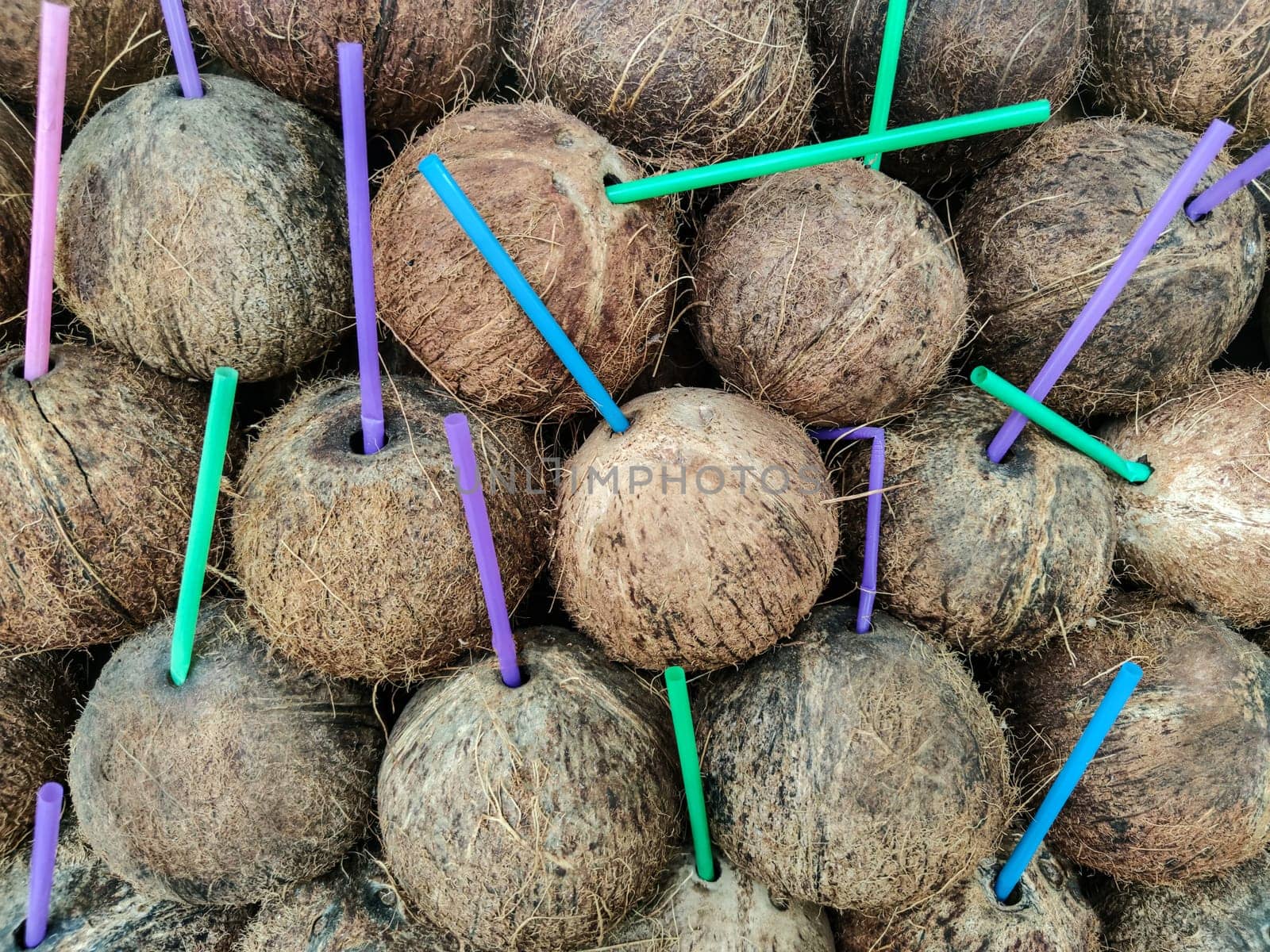 Coconut background with colorful plastic cocktail drinking tubes.