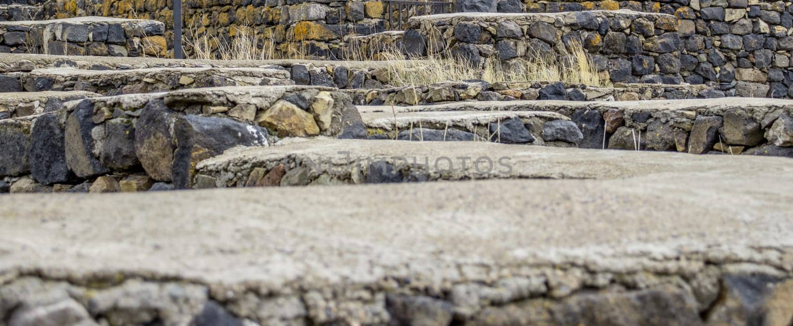 Real stone wall surface with cement concept photo. Stone labyrinth with yellow autumn grass. High quality picture for wallpaper