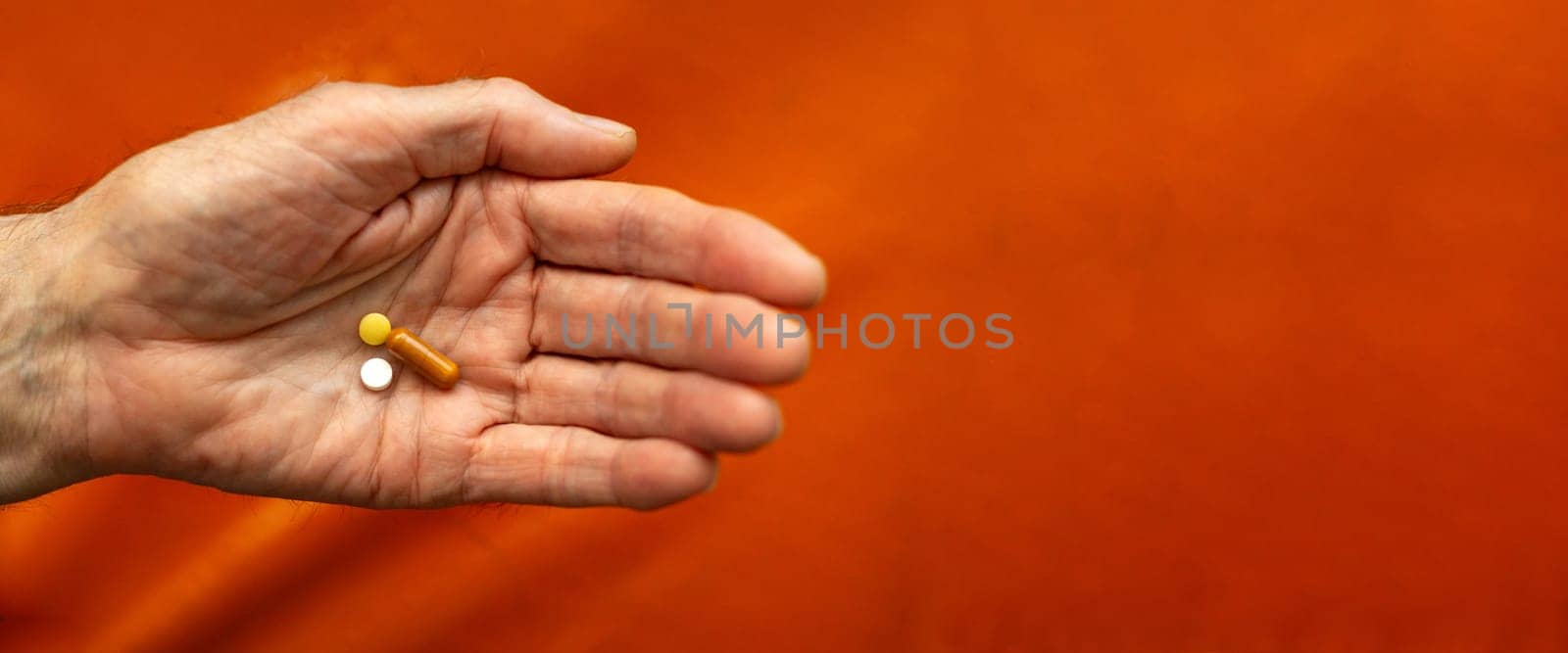 Close up view of senior male handholding pill. Supplements, longevity concept. Banner copy space