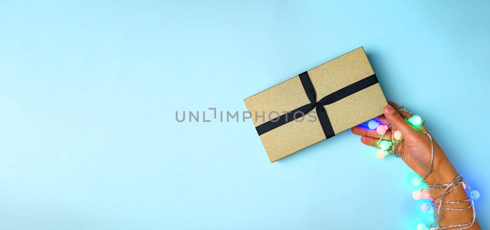 Handmade paper gift box with a gift for Christmas, New Year, on a blue background, top view. Banner, copy space