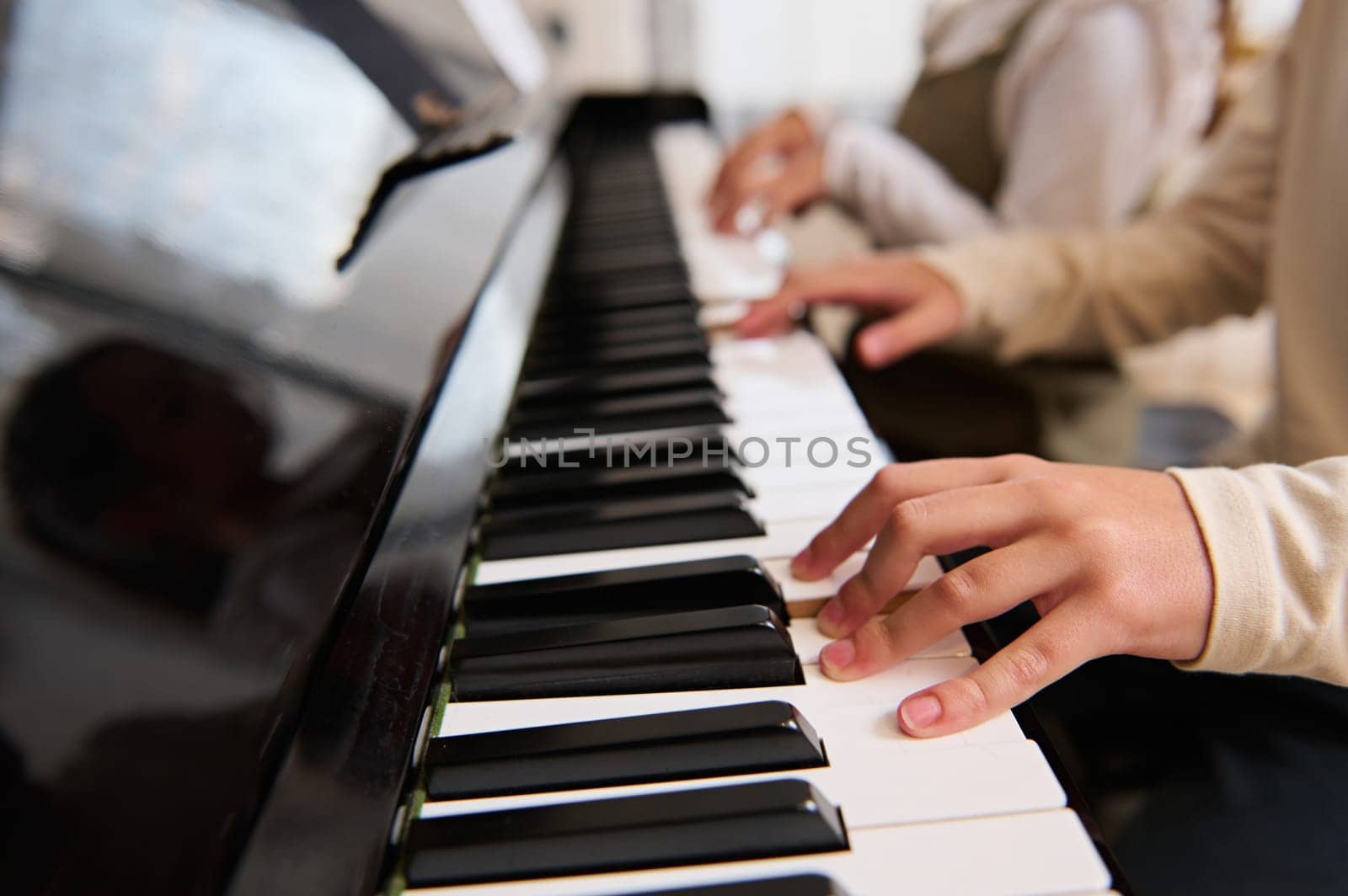 Close-up of kid's hands playing piano. by artgf