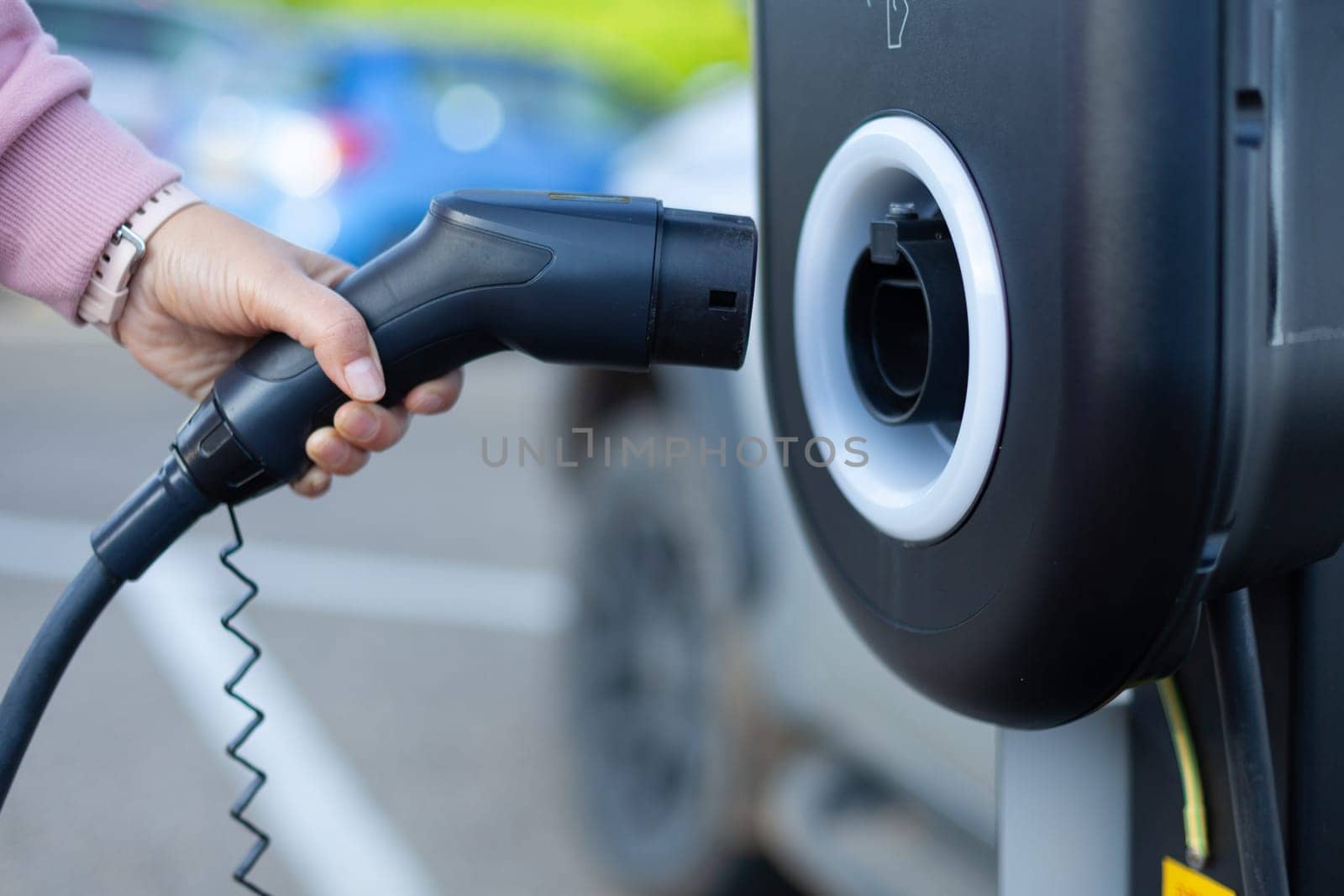 The girl's hand took a gas nozzle to charge an electric car. High quality photo