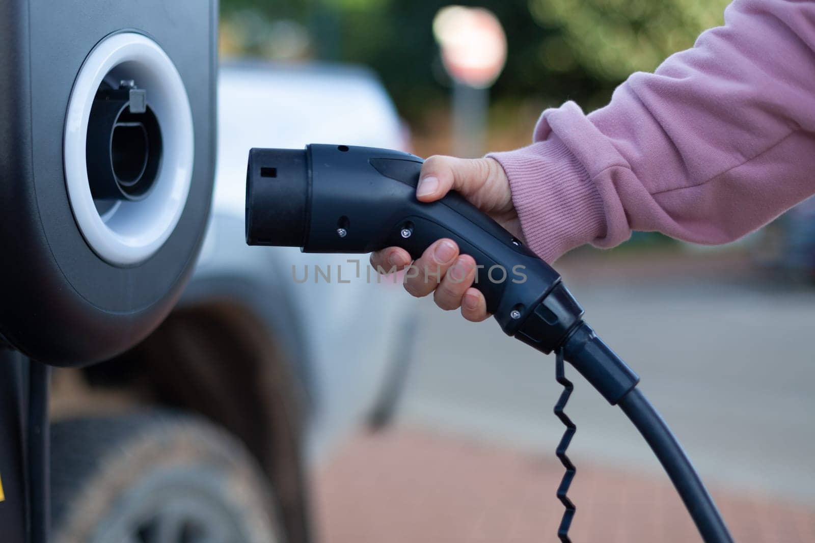 The girl's hand took a gas nozzle to charge an electric car. High quality photo