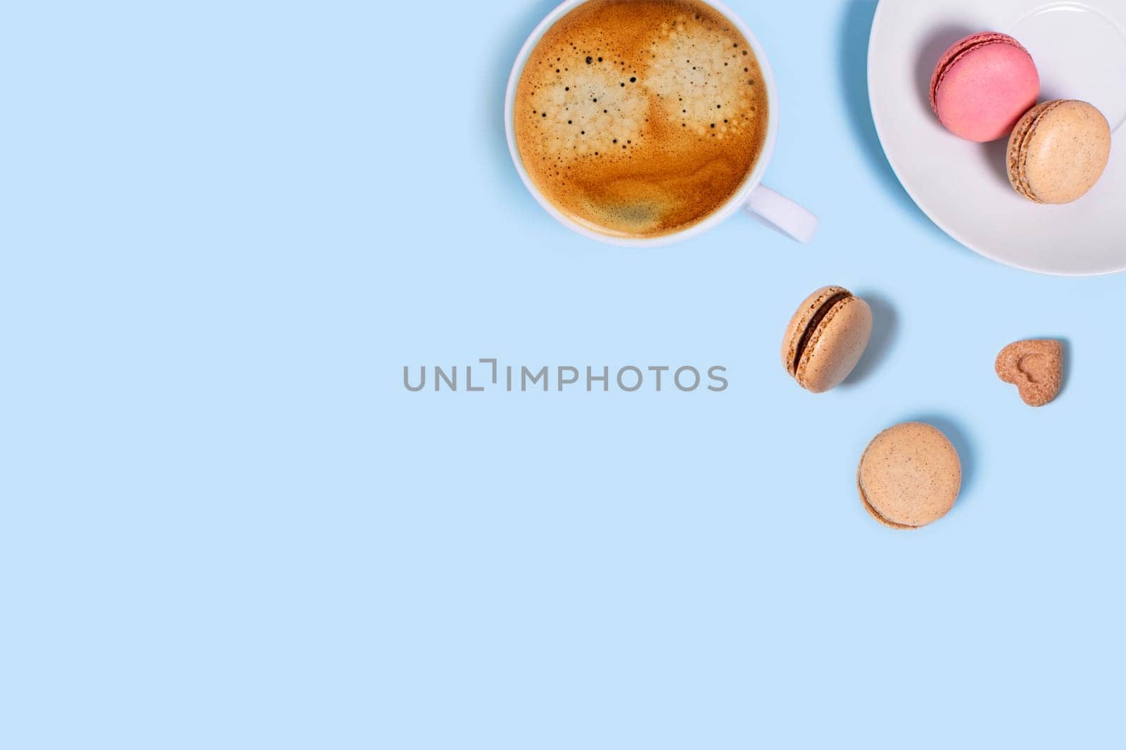 Blue background with macaroons and cup of coffee. Top view with space for your text.