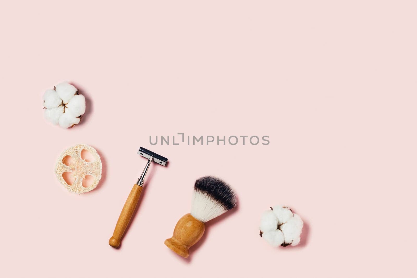 Bathroom accessories on pink background. Sponges, cotton flowers, shaving brush and razor. Flat lay, top view.