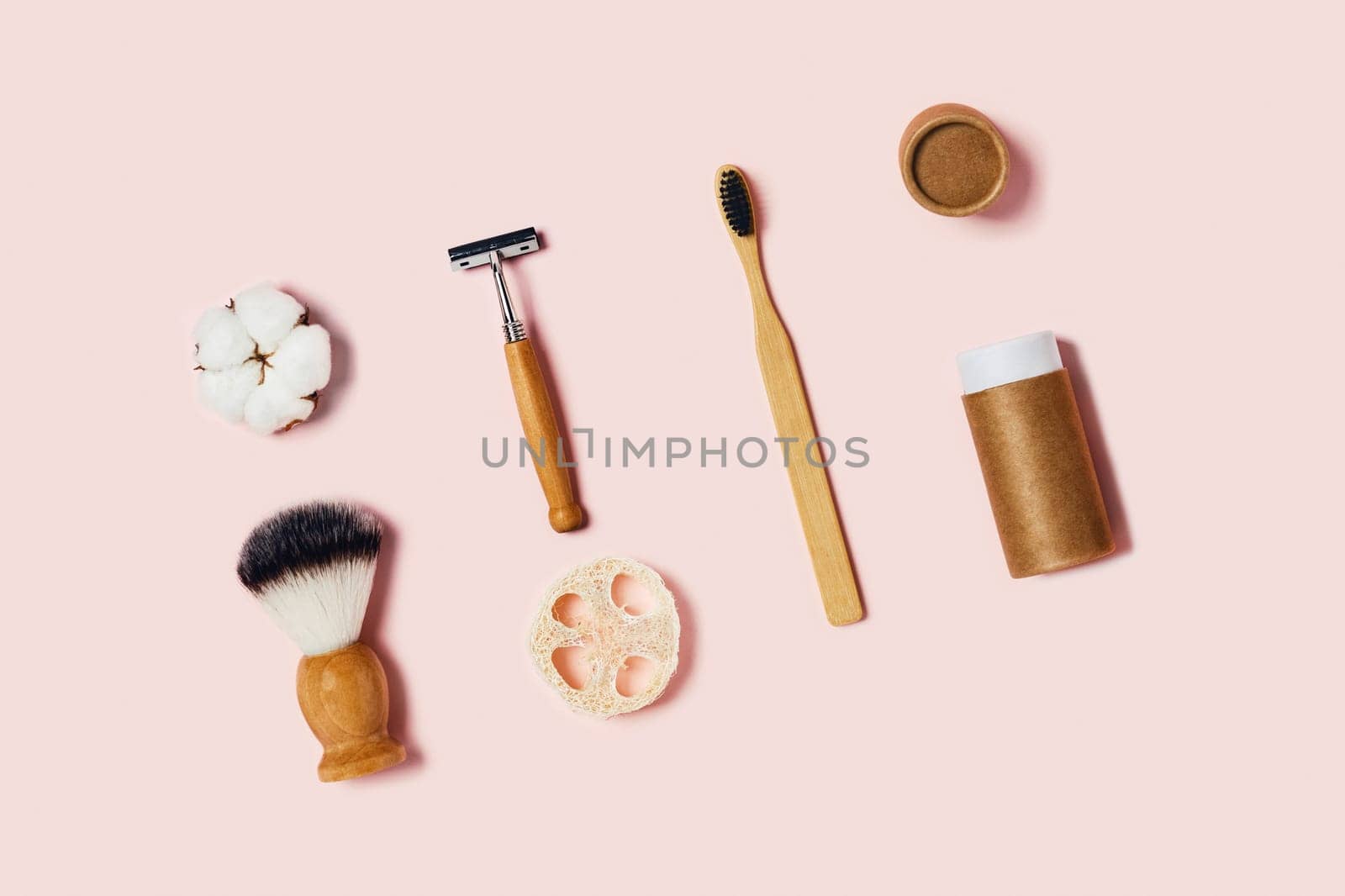 Bathroom accessories on pink background. Natural bamboo toothbrush, sponges, cotton flowers, shaving brush. Flat lay, top view.