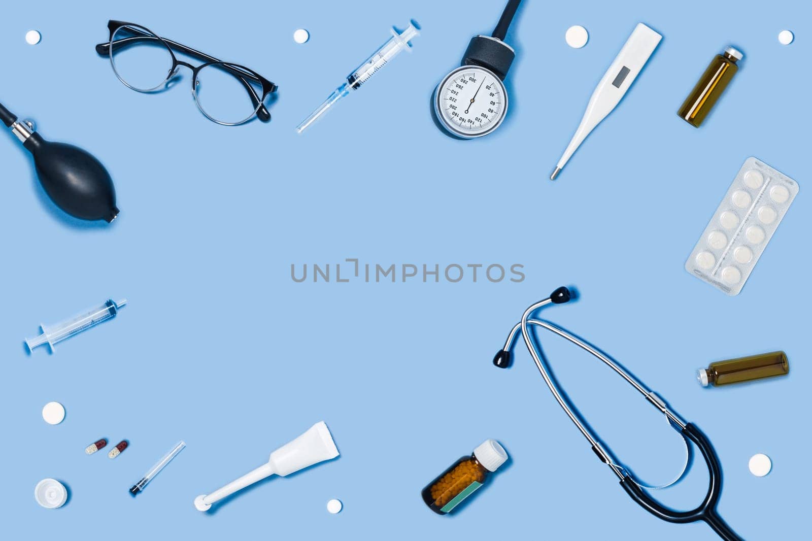 Medical blue background with different accessories: stethoscope, syringe and tablets.