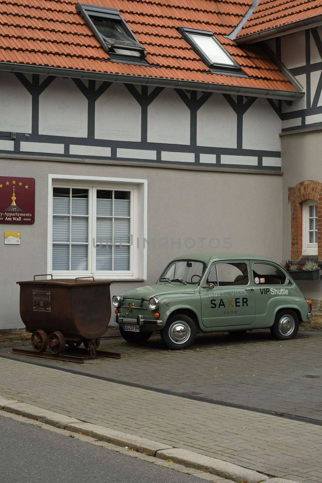 Vertical shot of a small vintage green FIAT 500 near a mining lorry in Goslar, Germany