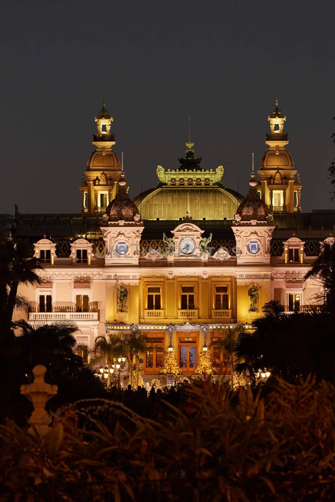 Monaco, Monte-Carlo, 12 November 2022: The famous square of Casino Monte-Carlo is at dusk, attraction night illumination, luxury cars, players, tourists, splashes of fountain. High quality photo