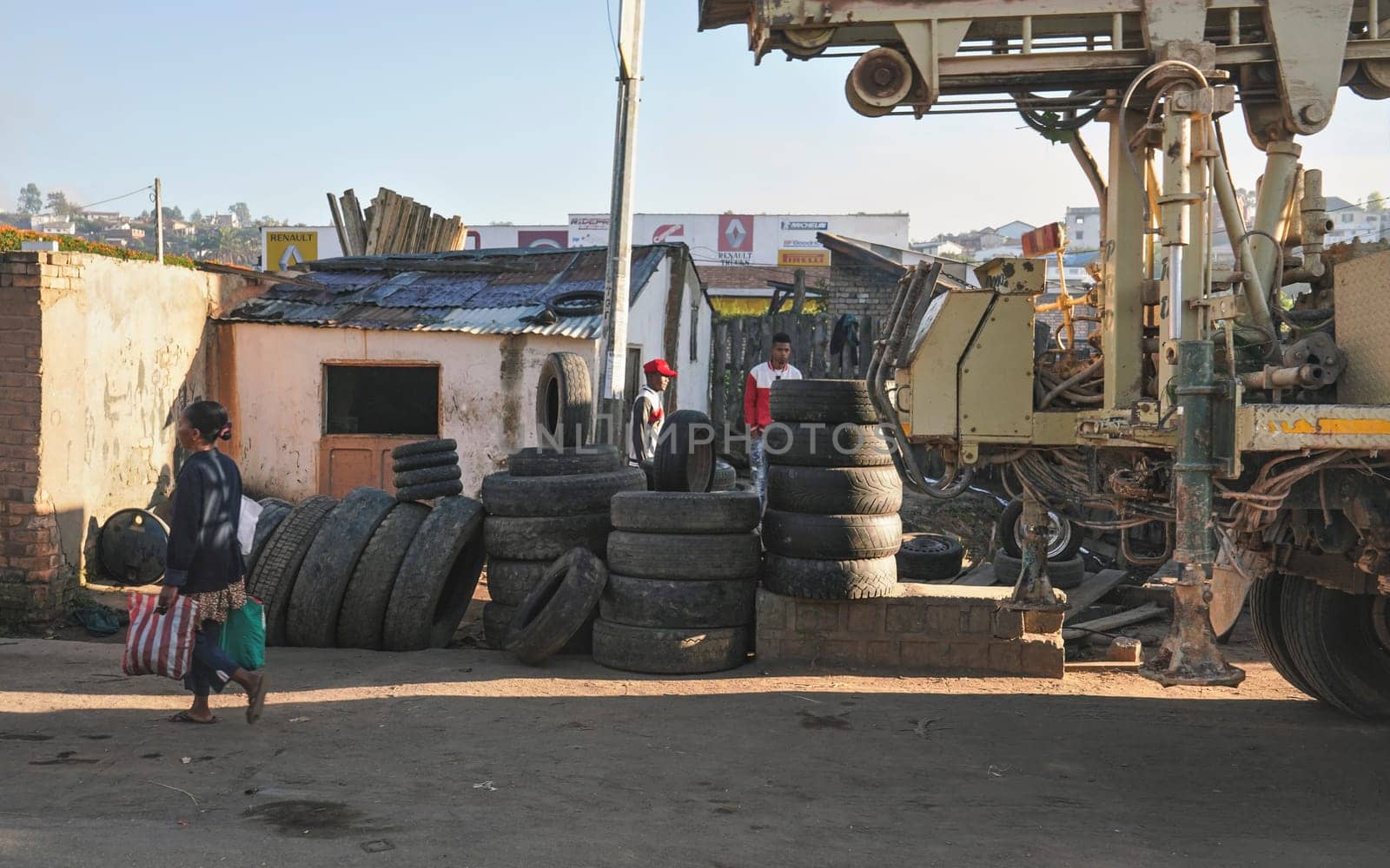 Fianarantsoa, Madagascar - May 06, 2019: Old tires by the road at the local garage repair workshop, construction vehicle on the right. Only few roads exist on Madagascar and are used by trucks mostly by Ivanko