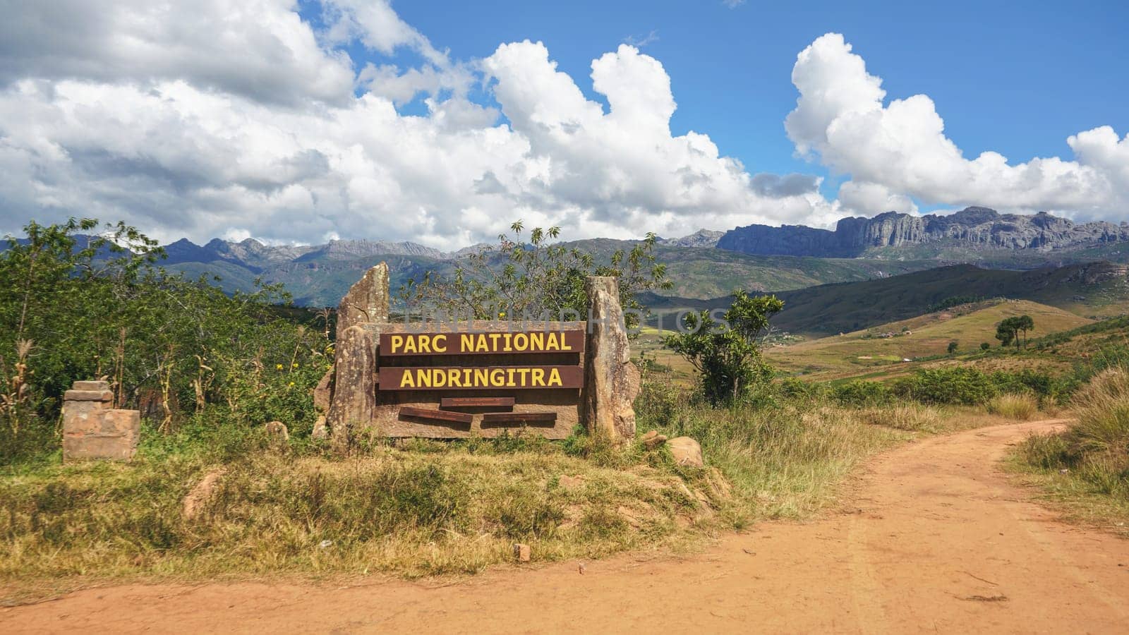 Andringitra National Park, Madagascar - April 27, 2019: Sign at the entrance road to park, mountain massif in distance with dramatic clouds above. Pic Boby aka. Imarivolanitra, highest peak - is there by Ivanko