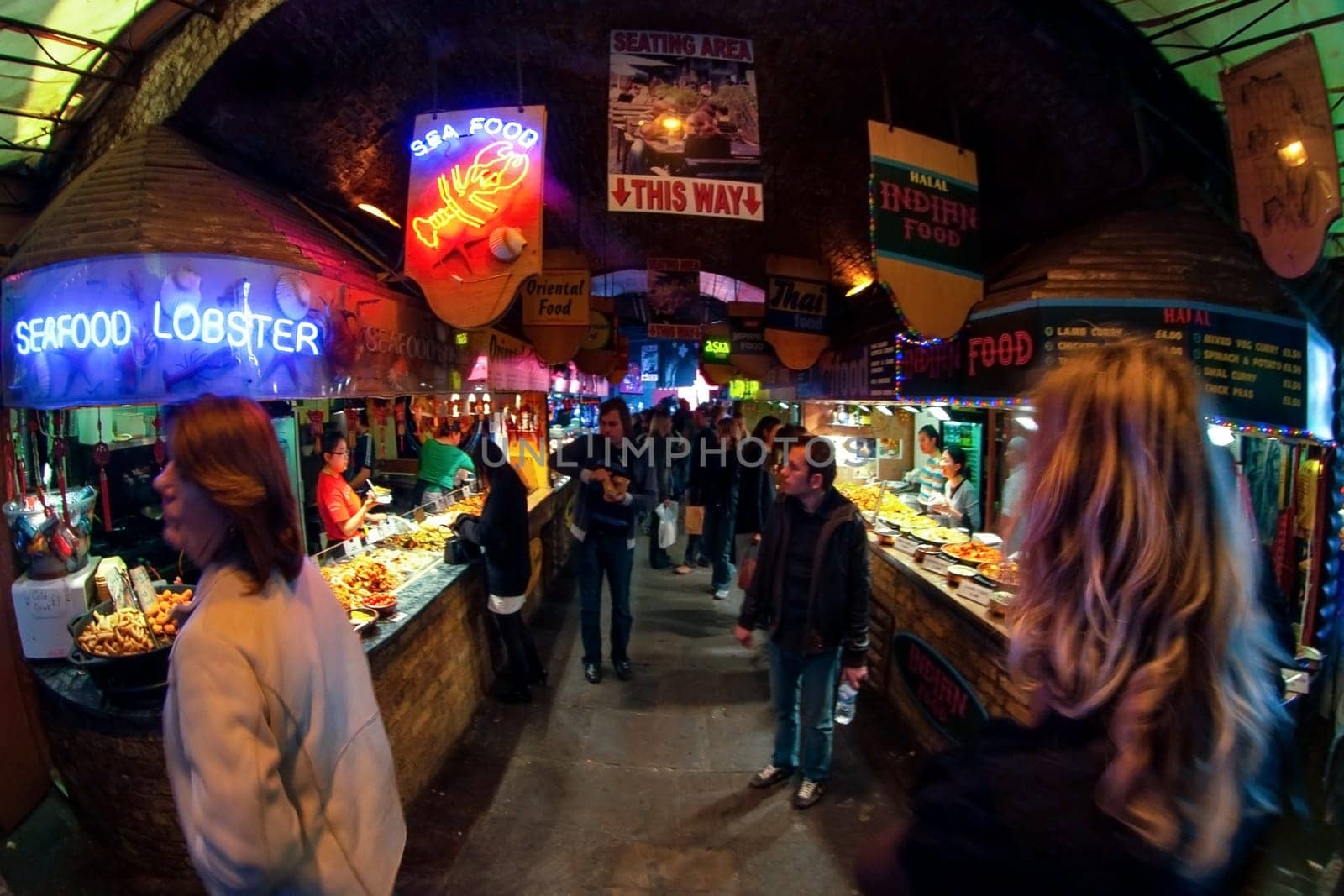 London, United Kingdom - April 01, 2007: Unknown shoppers walking near street food stalls at Camden Lock, famous market at UK capital. Extreme wide perspective (fisheye) photo