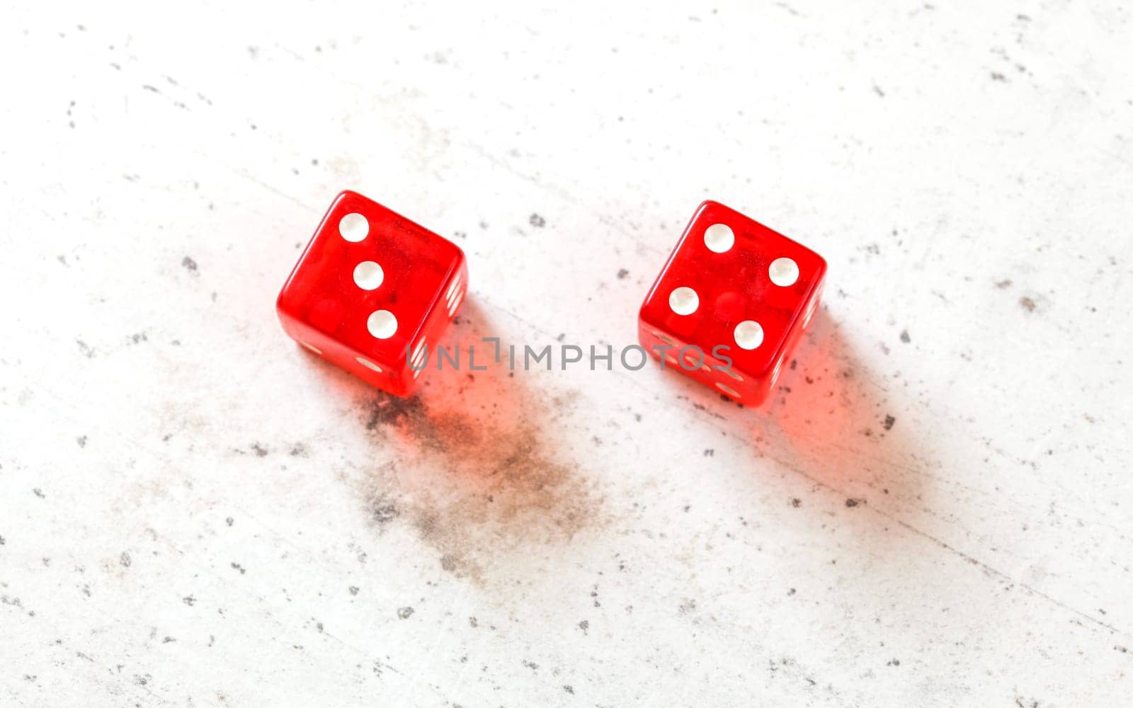 Two red craps dices showing Natural or Seven Out (number 3 and 4) overhead shot on white board