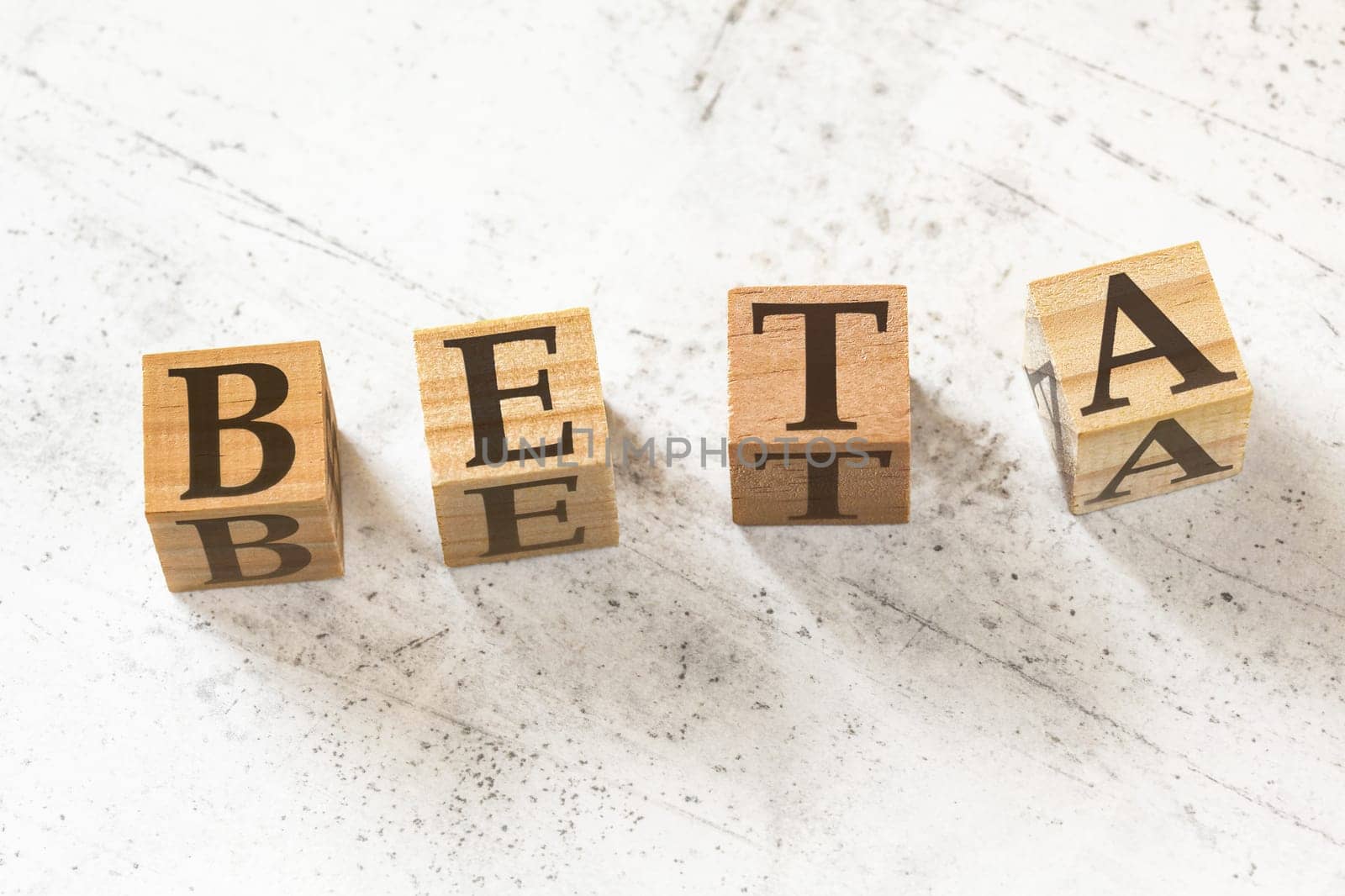 Four wooden cubes with word BETA (coefficient to measure volatility in finance) on white working board.