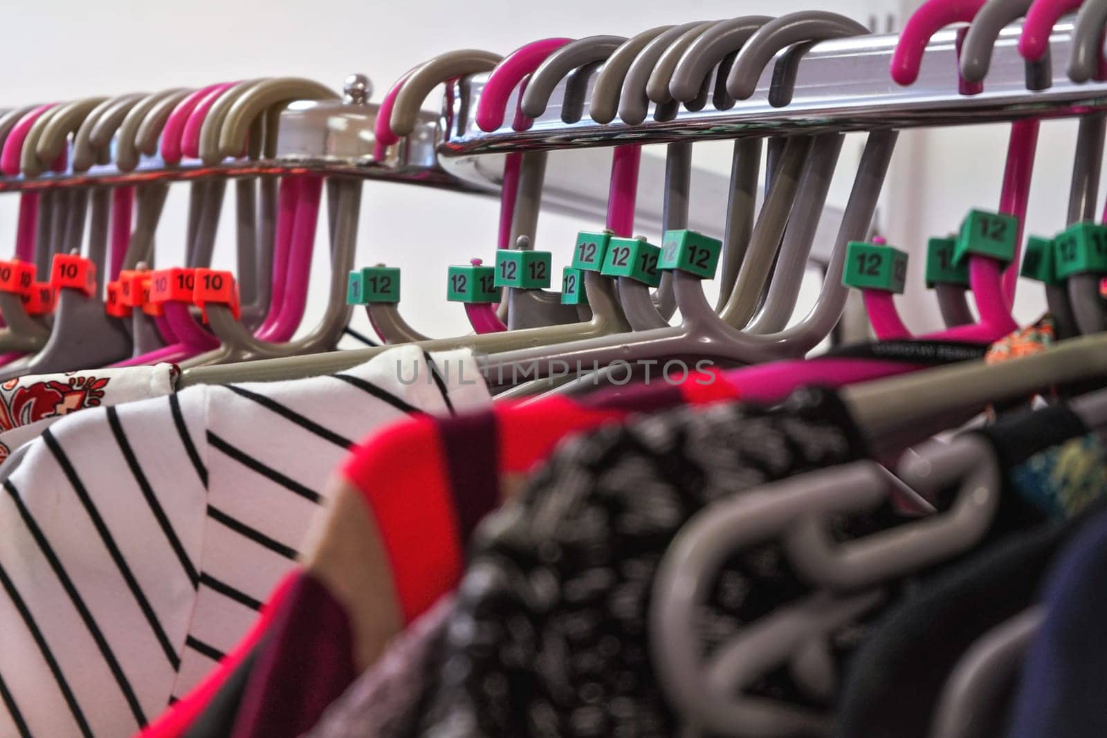 Close up on hangers with various women clothing in charity thrift shop