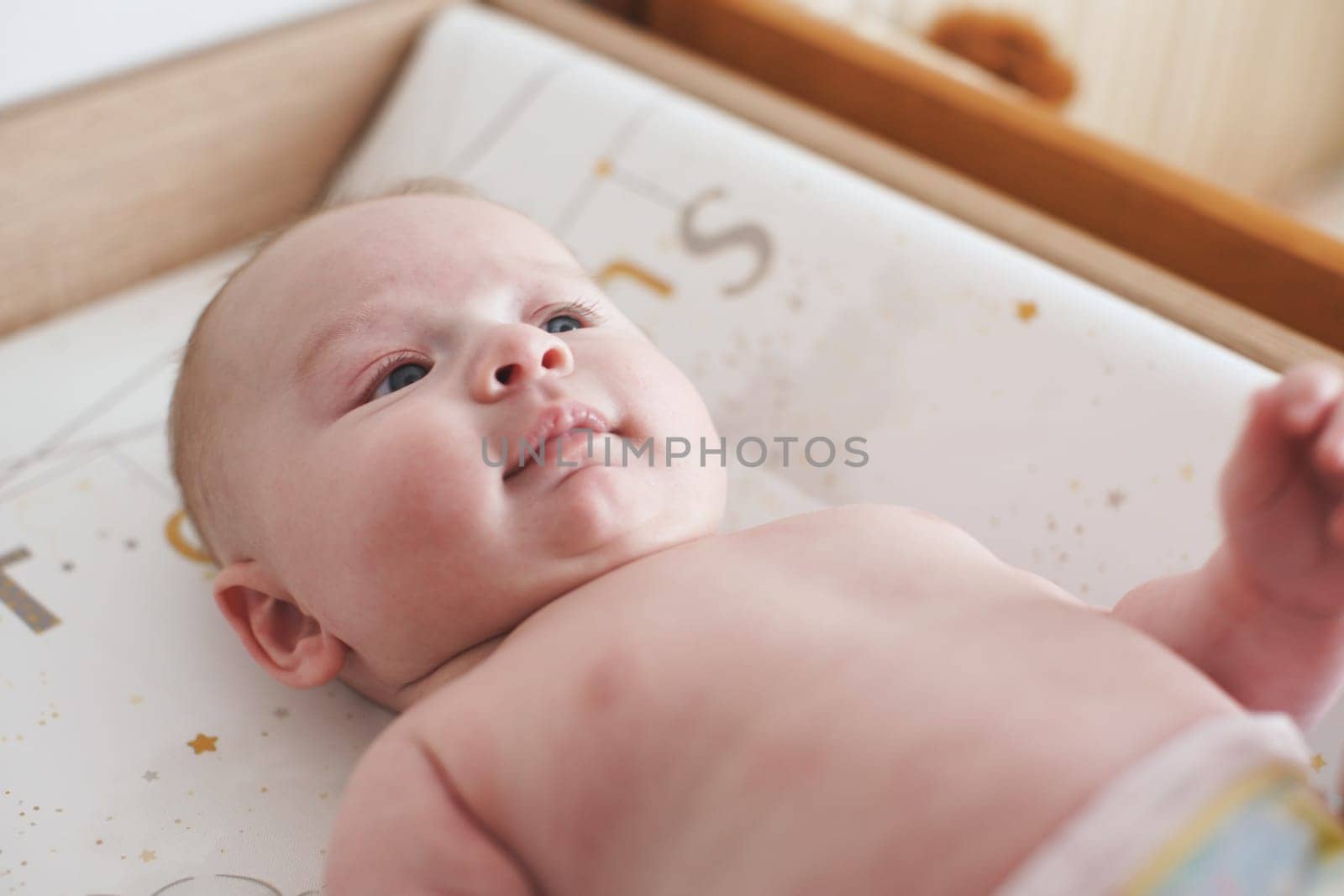 4 months old infant baby boy on changing table, detail on his face by Ivanko