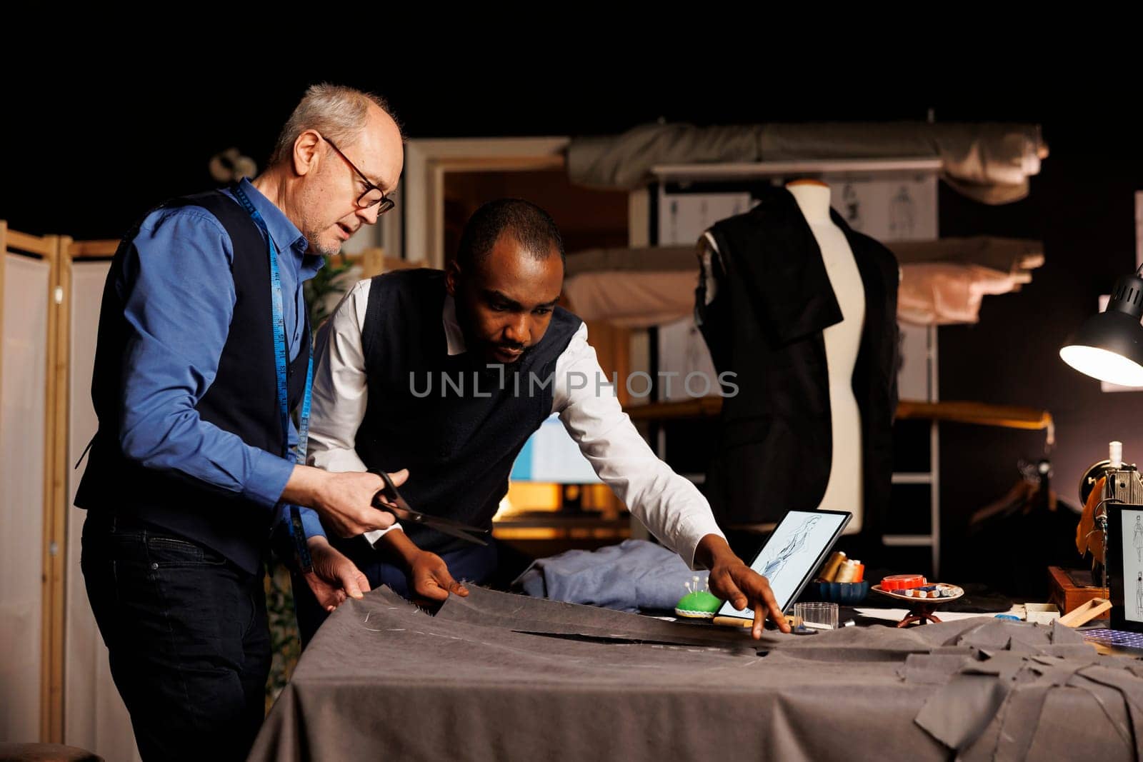 Dressmakers preparing clothing material by DCStudio