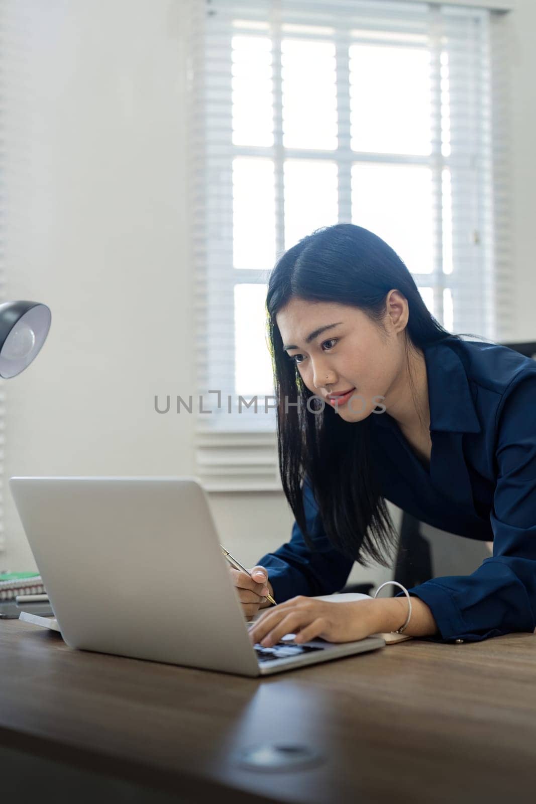 Professional businesswoman working at her home via laptop, young female manager using computer laptop while sitting on desk, work process concept by nateemee