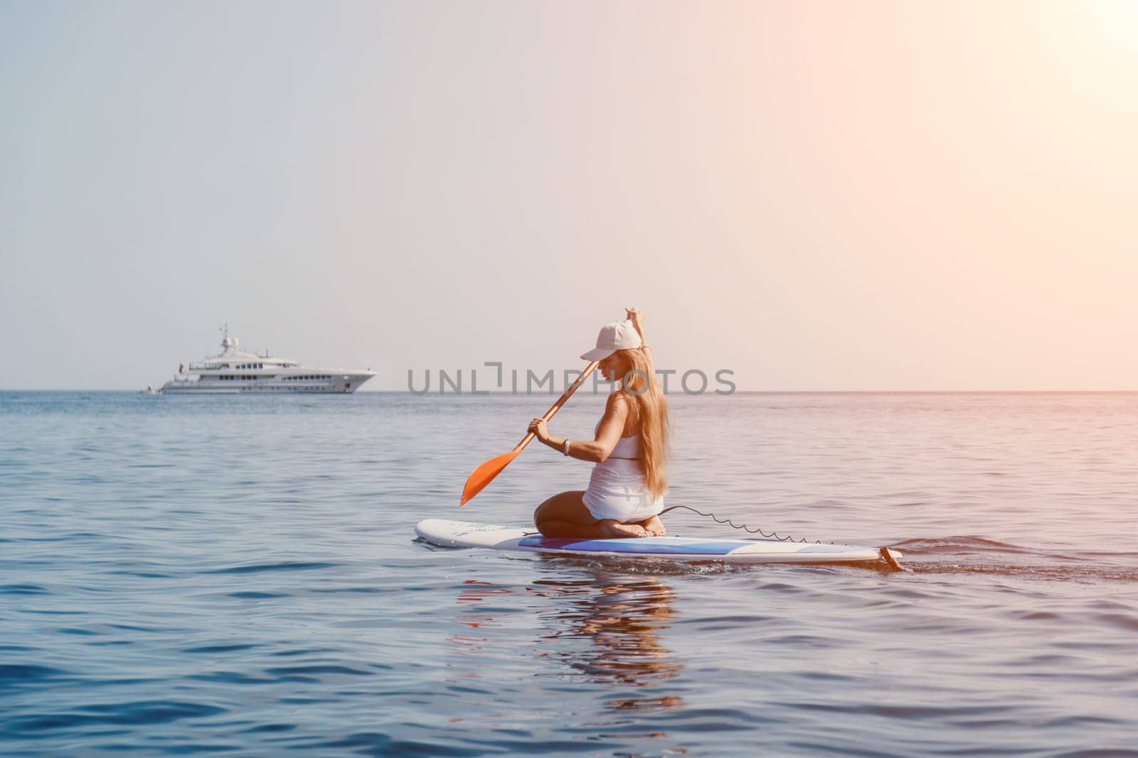 Woman sea sup. Close up portrait of happy young caucasian woman with long hair looking at camera and smiling. Cute woman portrait in bikini posing on sup board in the sea by panophotograph