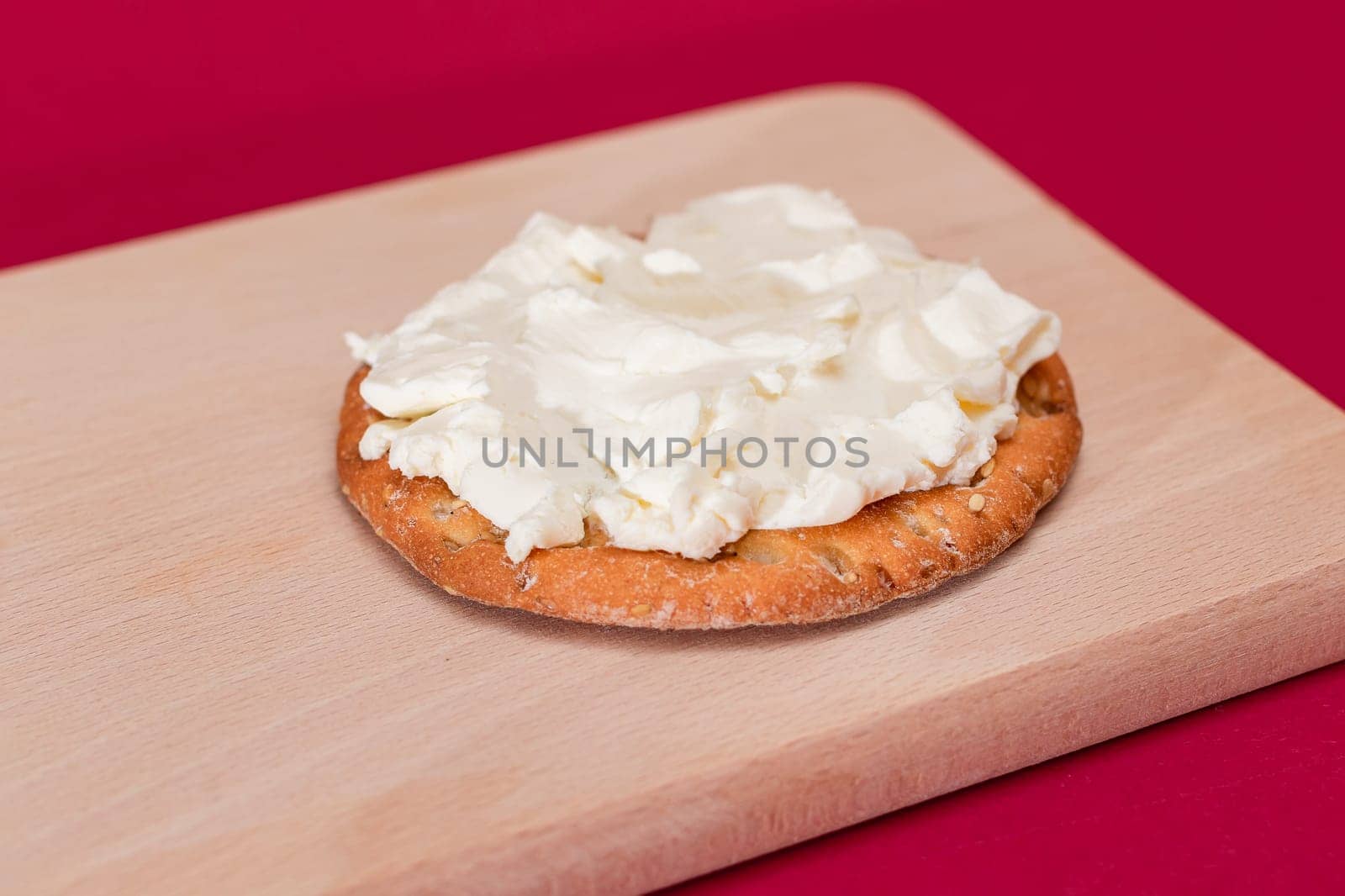 Crispy Cracker Sandwich with Cream Cheese on Wooden Cooking Board on Magenta Background