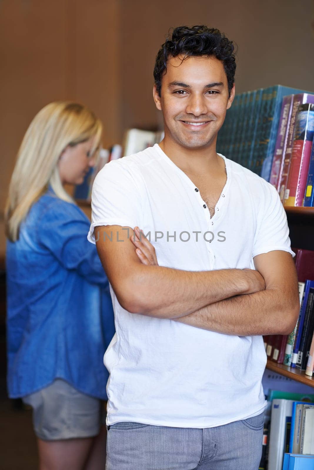Portrait, arms crossed or happy man in a library for knowledge or development for future growth. Scholarship, education or male student with smile or pride for studying or learning in college campus.